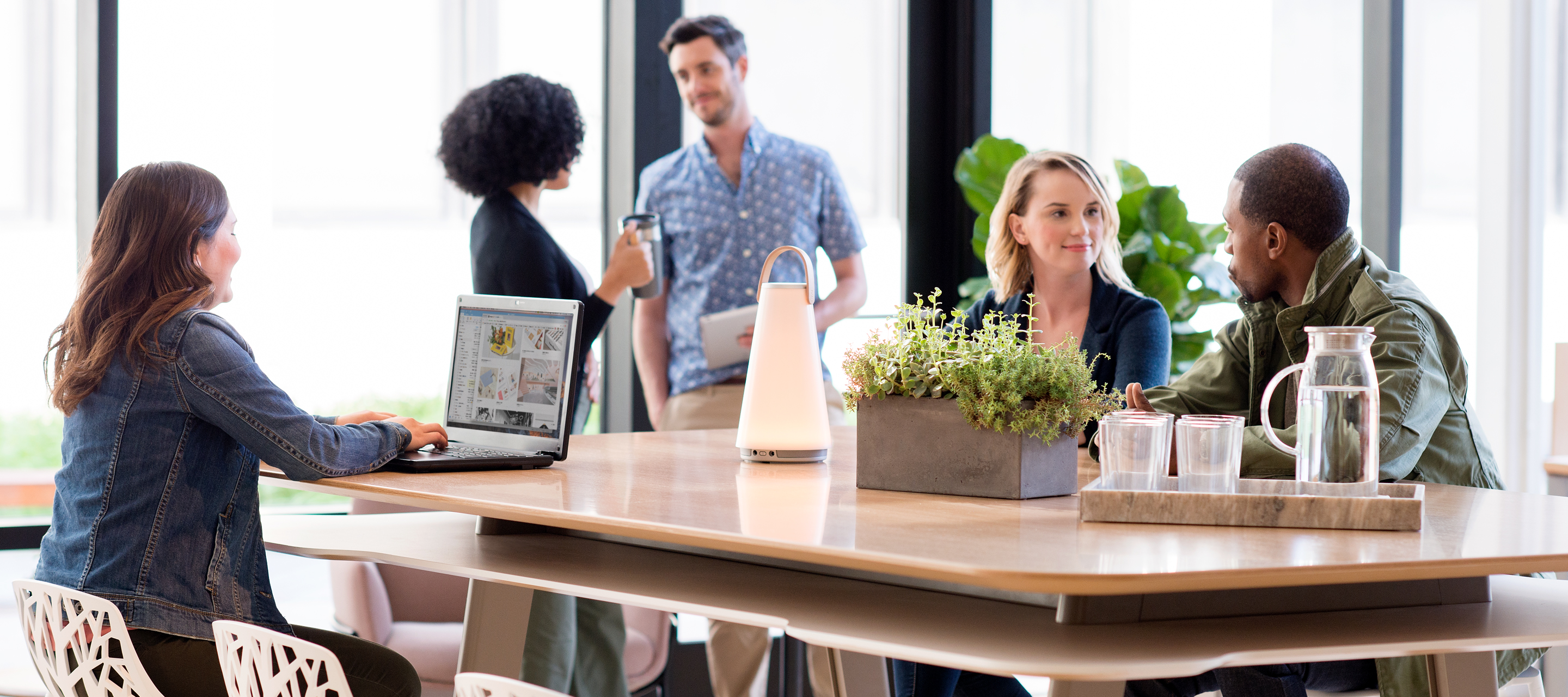 People socialising on a Haworth Planes table with Uma lamp