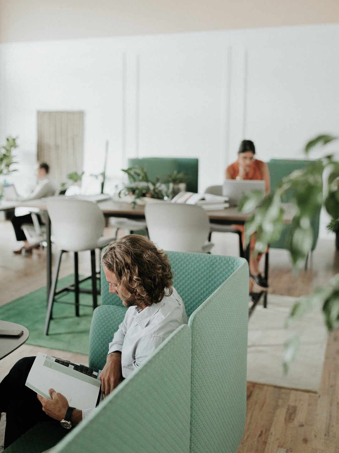 office lounge seating area with worker reading a magazine on a sofa