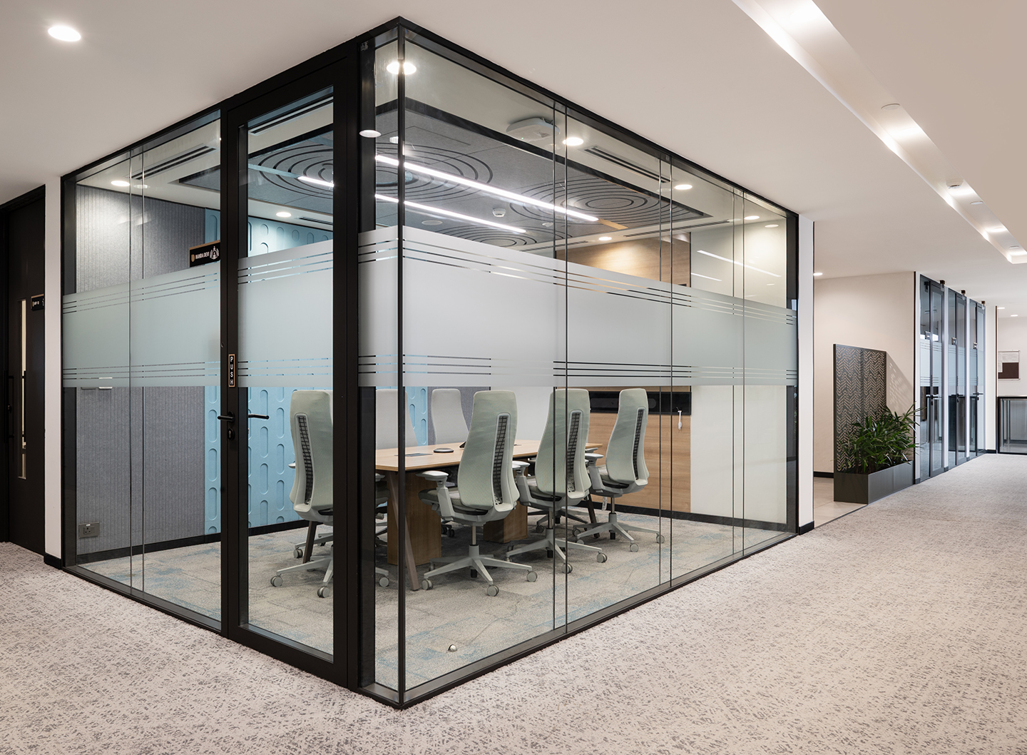 Glass-enclosed meeting rooms balance openness and confidentiality.