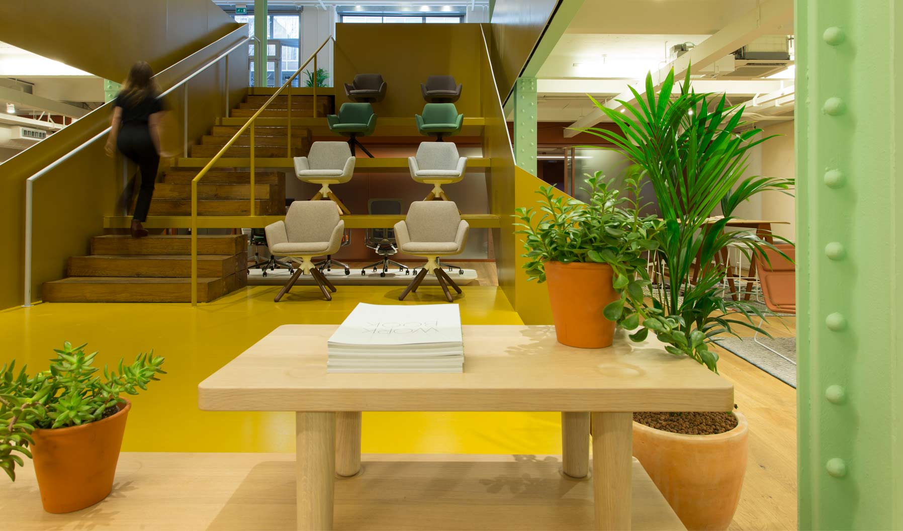 The central stairwell acts as a seating gallery, displaying Poppy chairs in a range of colors.