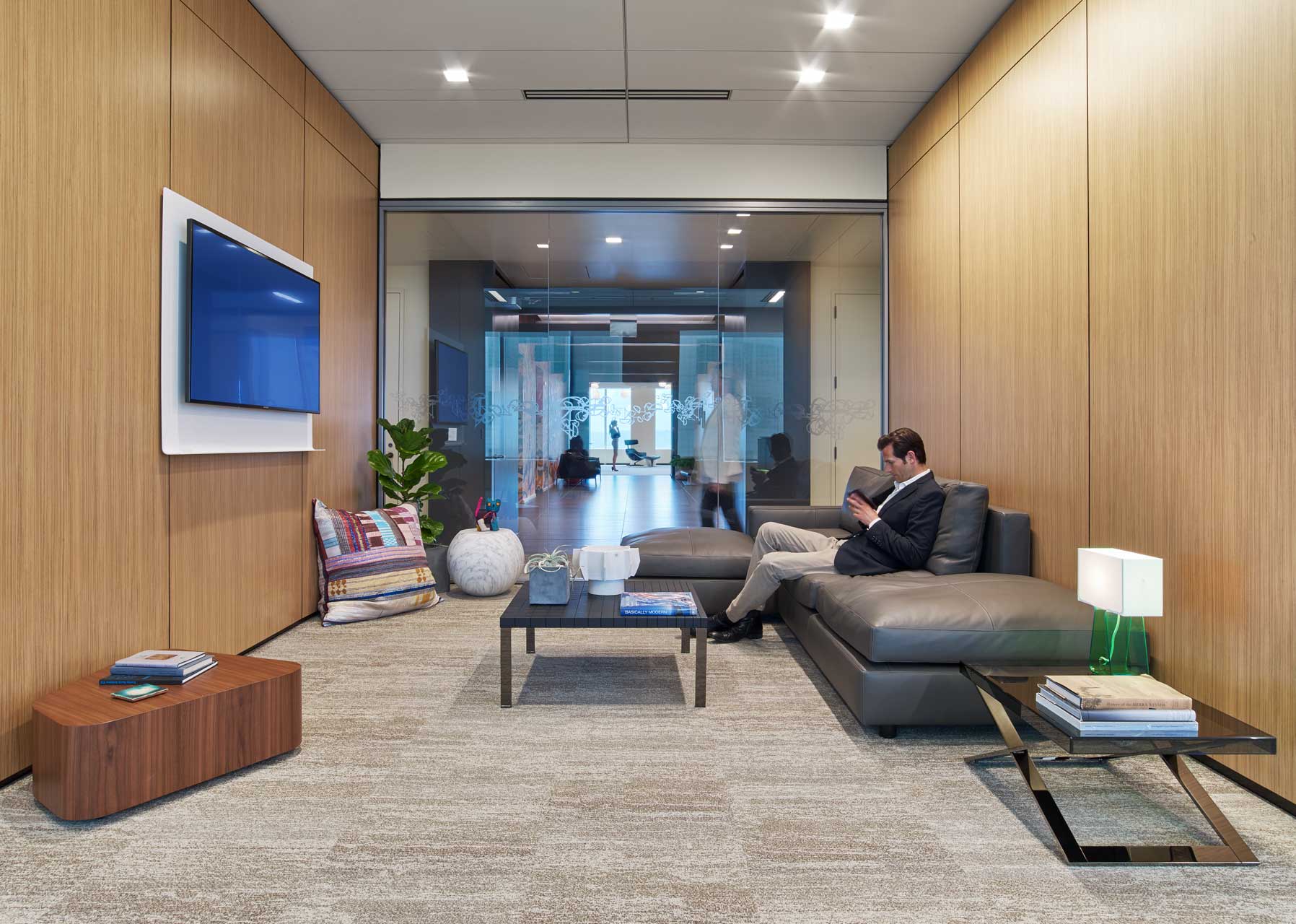 La position assise et détendue dans cette zone permet de se ressourcer ou favorise la collaboration dans un environnement lounge grâce à la technologie. Le canapé en cuir et les murs en bois apportent de la convivialité à cet environnement ouvert.