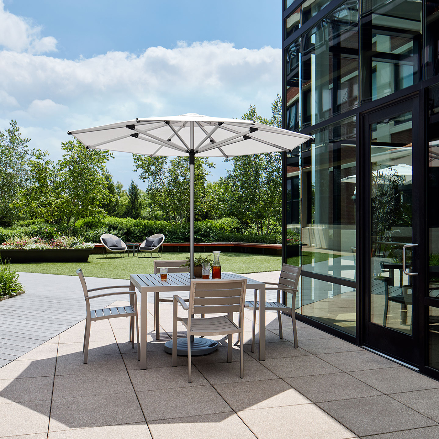 Haworth Janus Titan Umbrella Accessories in outdoor office seating area covering a table next to glass building 