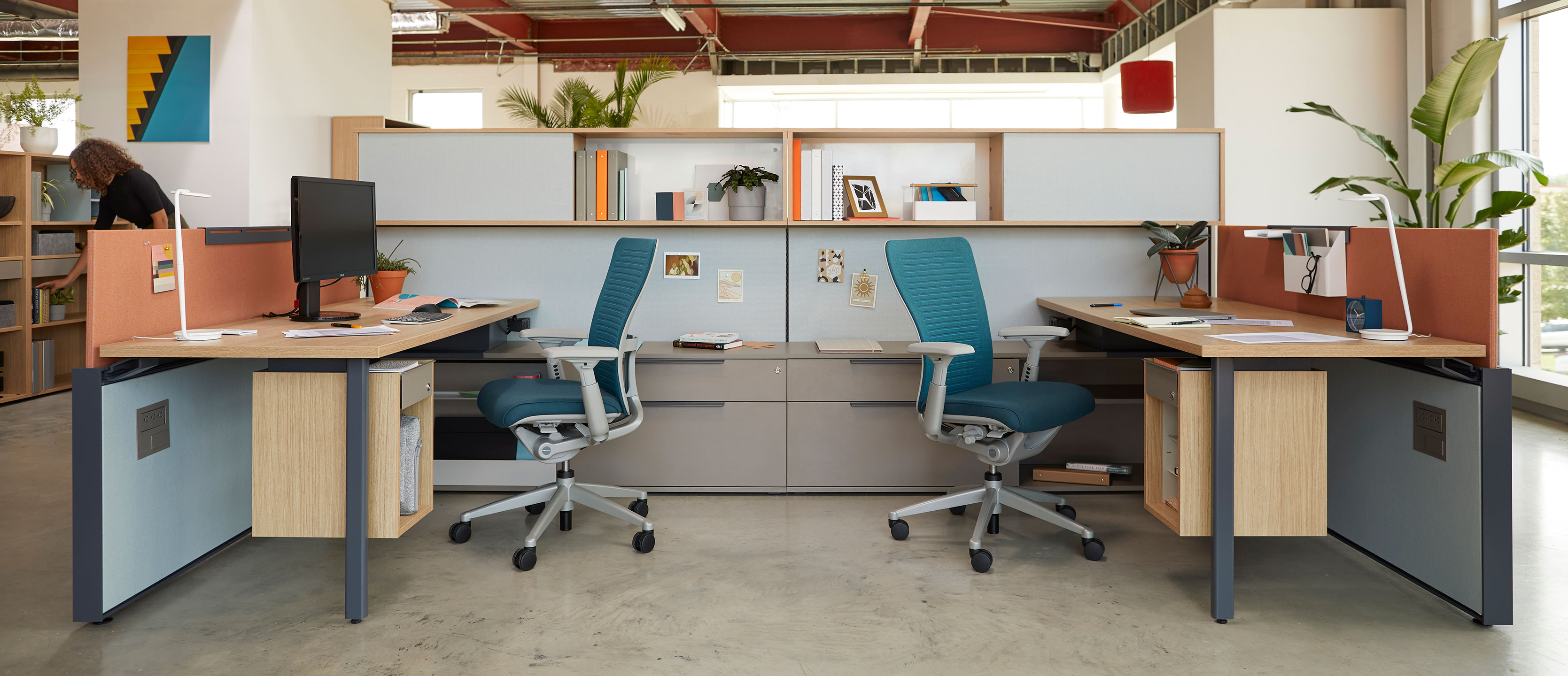 Be_Hold individual workspaces with file drawers and bookshelves with Zody chairs in blue. 