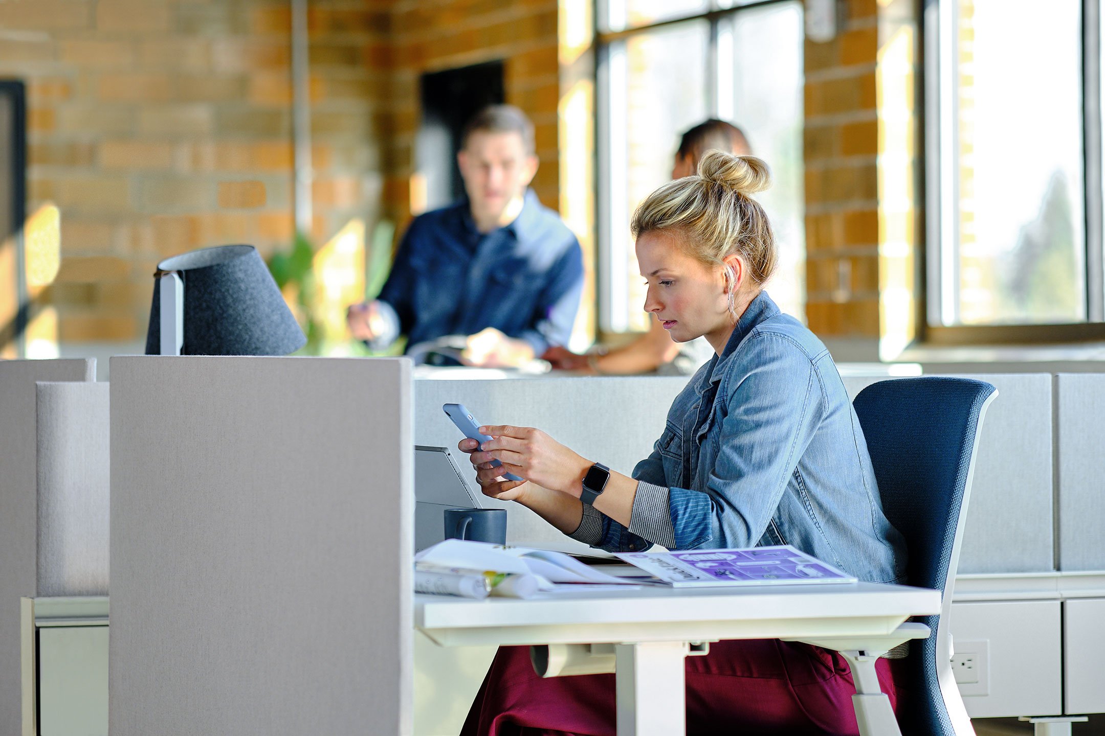 Haworth Belong Work Tools Accessories on a desk with an employee looking at their phone