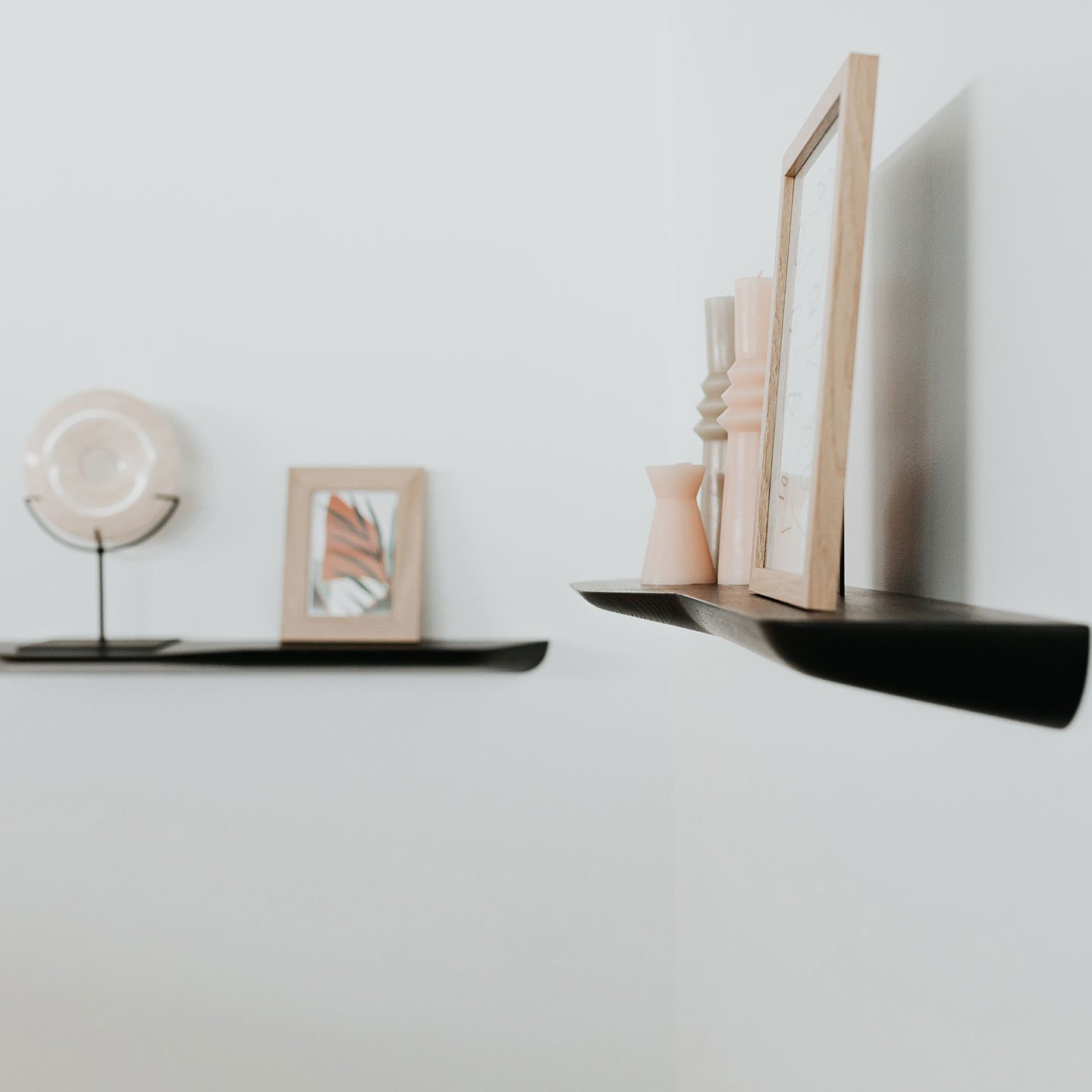 Haworth Buzziplank Accessories shelves in Ash Black stained with a wooden frame on it and candles on a white wall