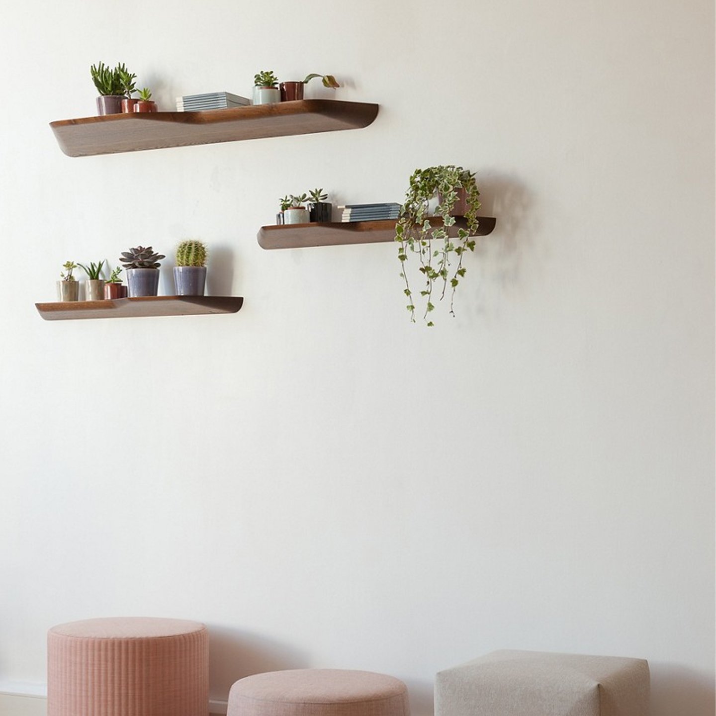 Haworth BuzziPlank Accessories shelves in ash walnut stained above ottomans on a white wall