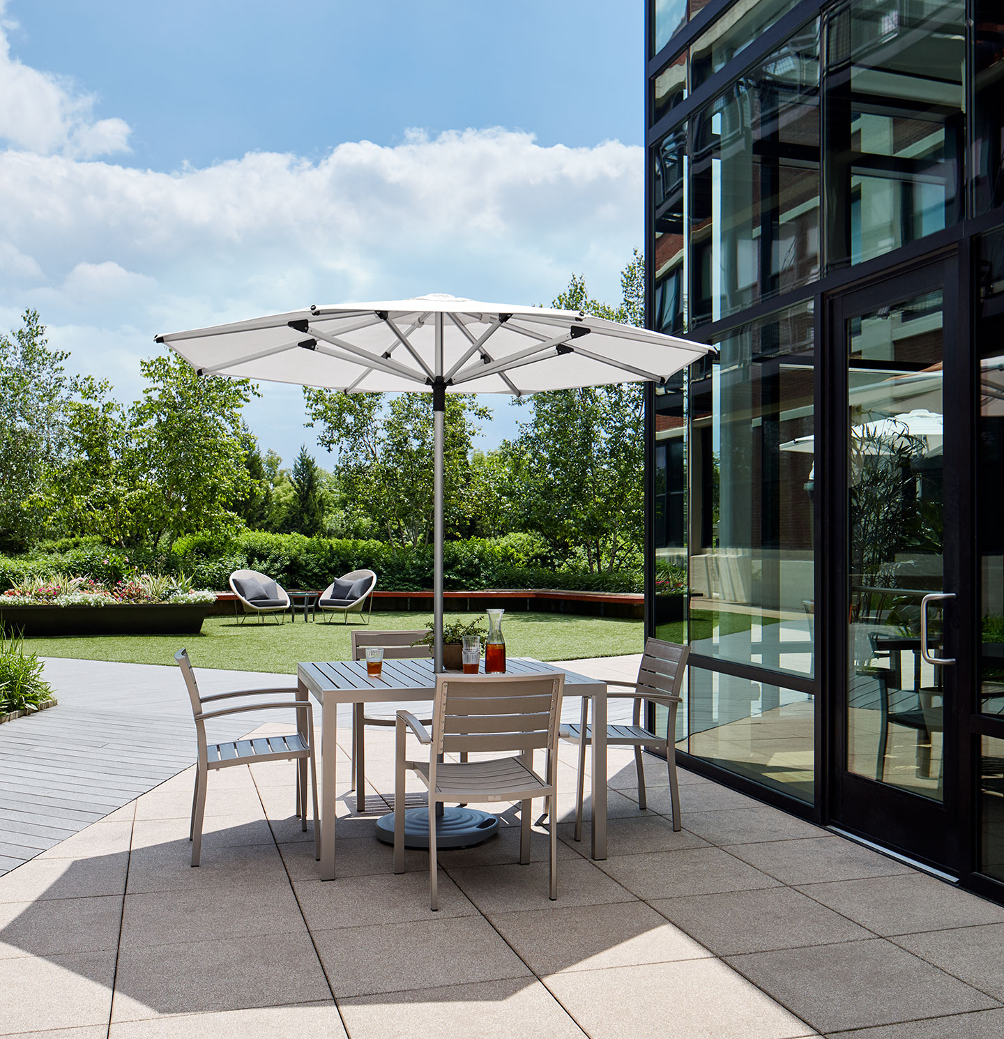 Haworth Janus Titan Umbrella Accessories in outdoor office seating area covering a table next to glass building 