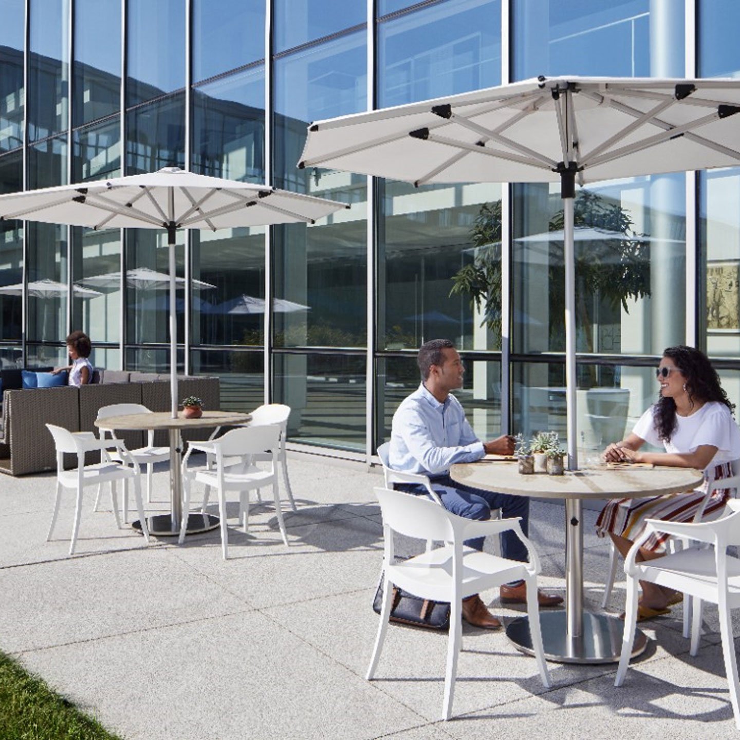 Haworth Janus Titan Umbrella Accessories in outdoor office seating area covering a table next to glass building 