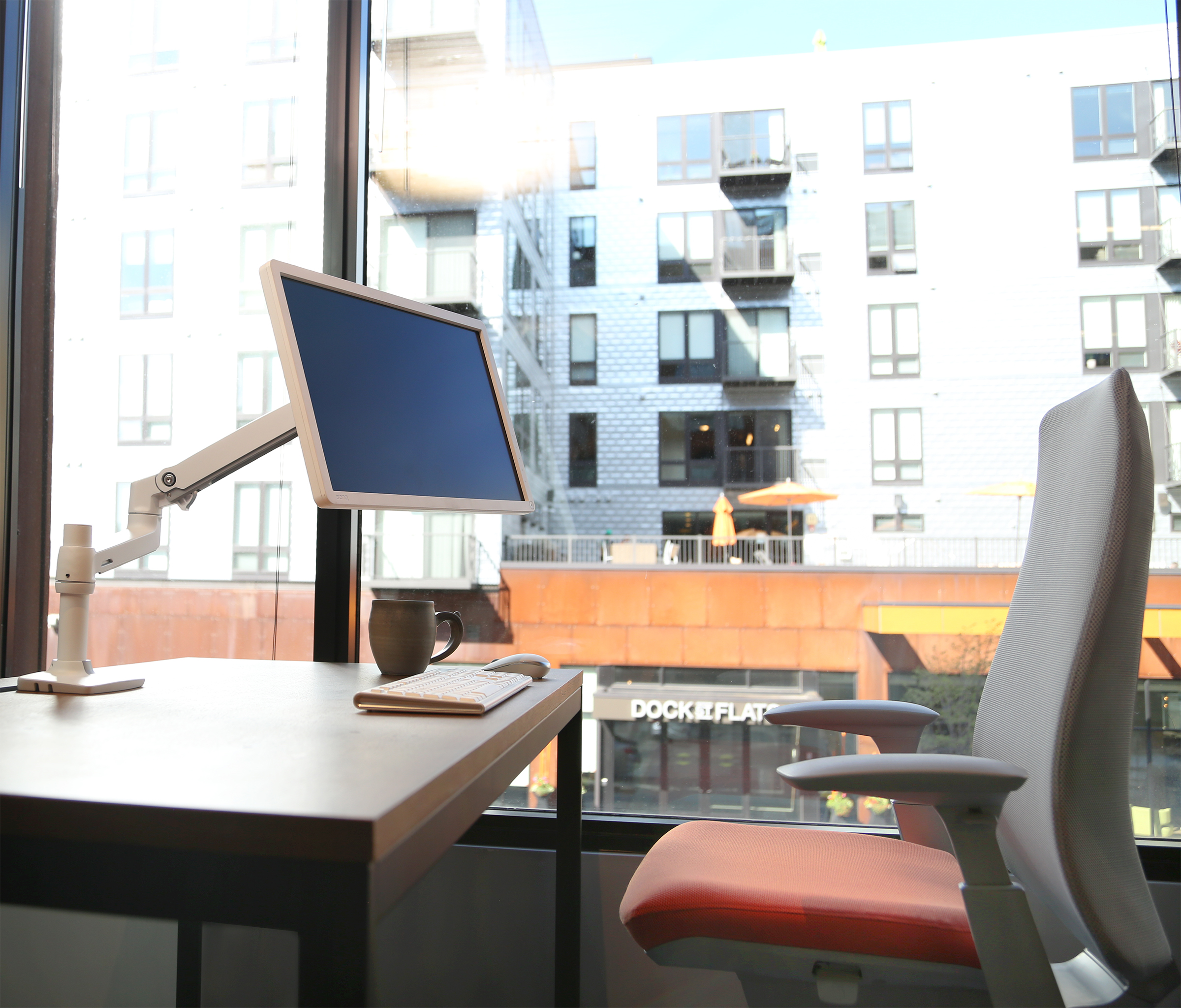 Haworth Monitor Arm Accessories at a desk with fern chair overlooking a city street