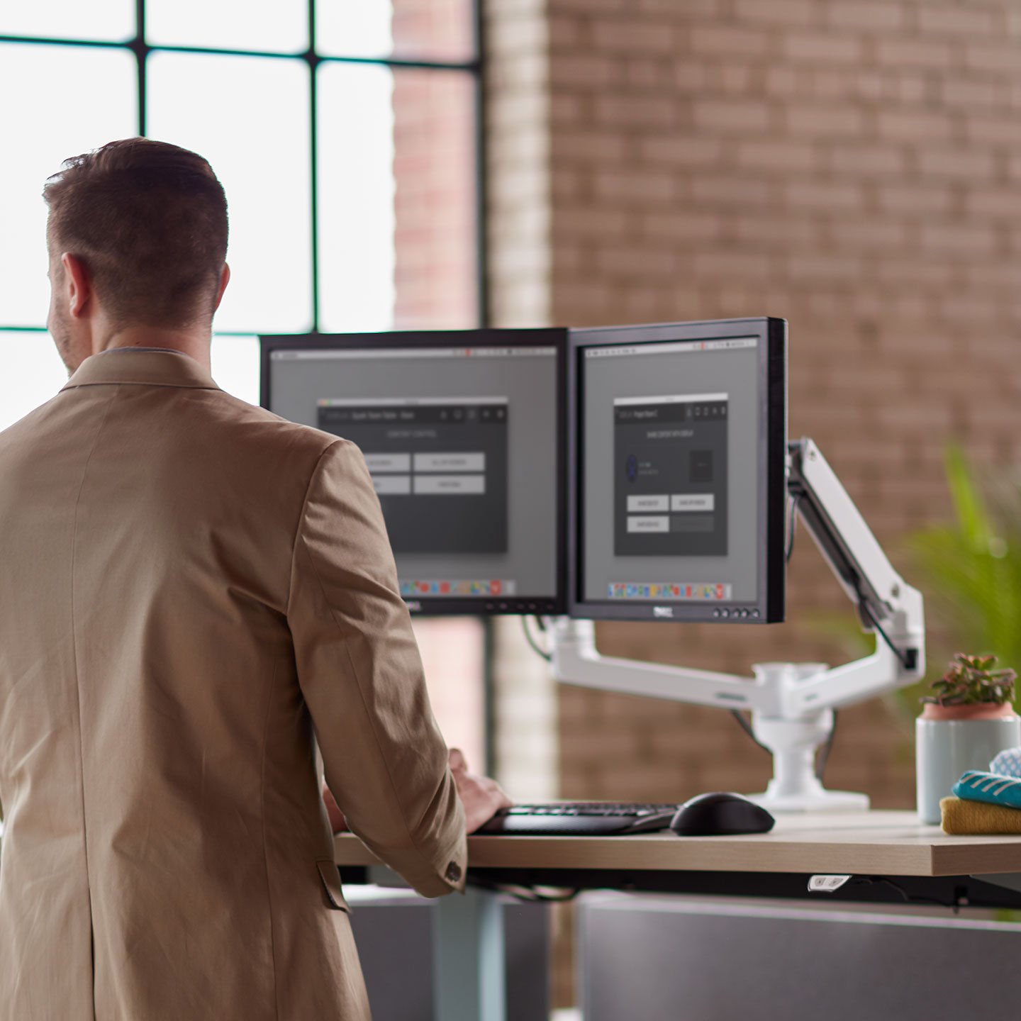 Haworth Monitor Arm Accessories at a desk space with dual monitors and employee working 