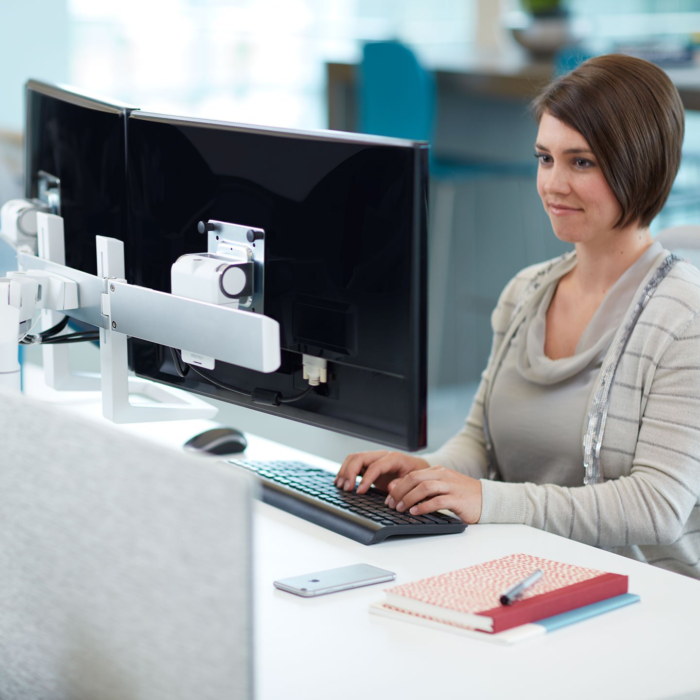 Haworth Monitor Arm Accessories at a desk with employee working on dual monitors