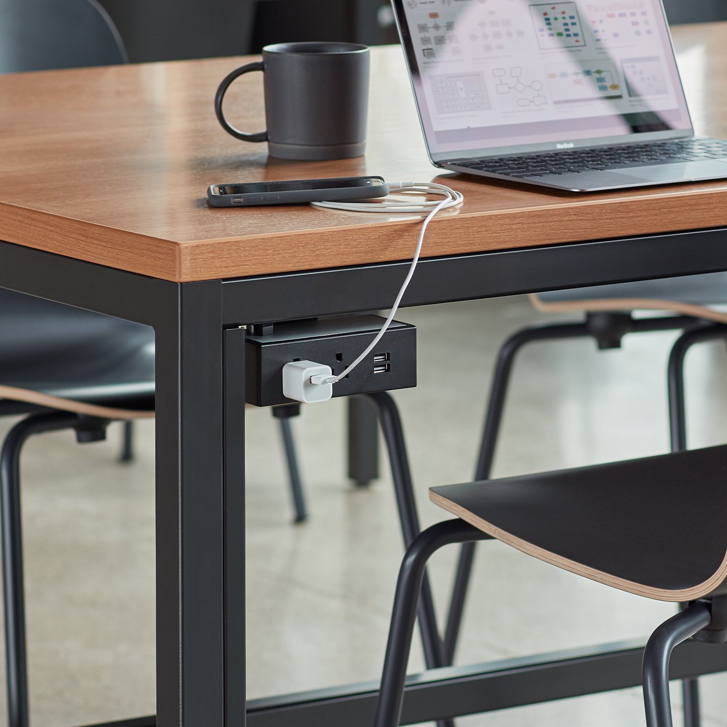 Haworth Workstation Power Solutions Accessories attached to the bottom of the desk in black color with phone plugged into usb port with laptop and coffee on desk