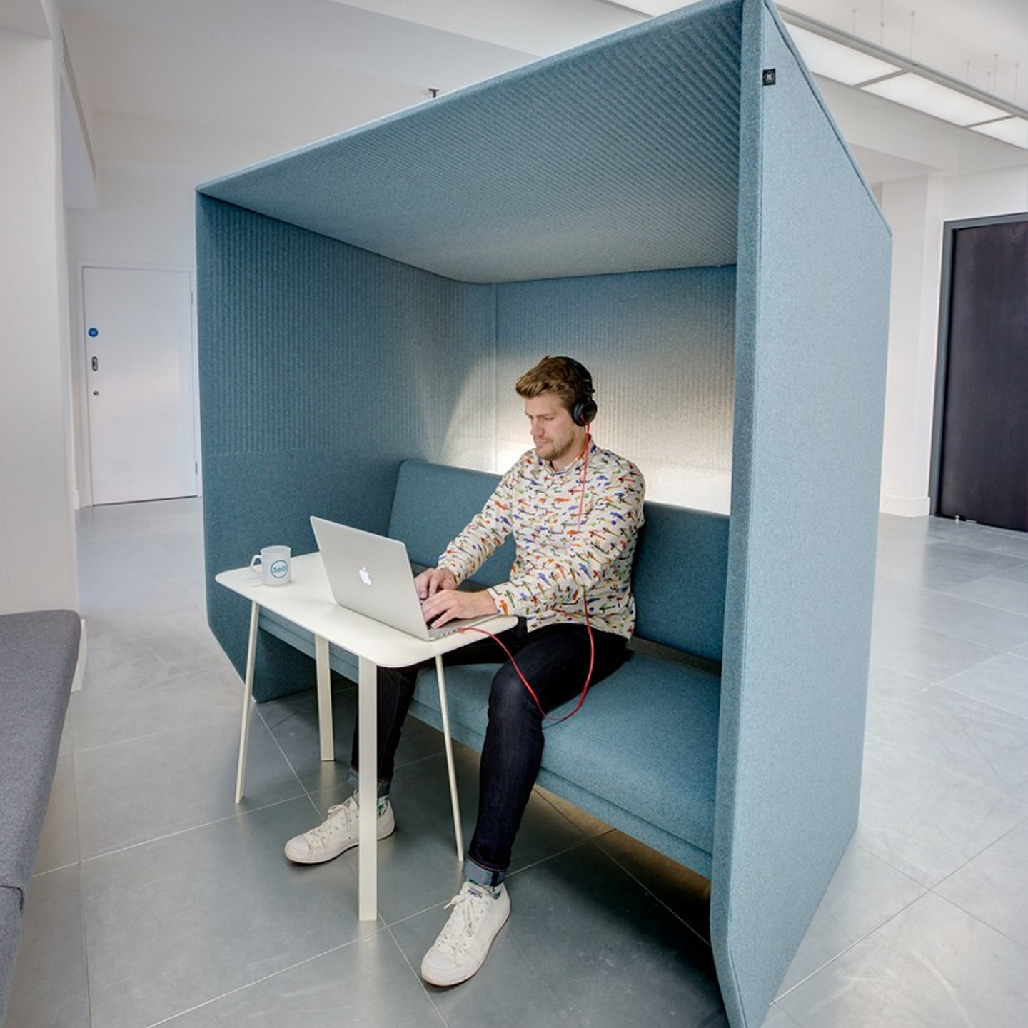 Haworth BuzziHub Booth in blue color with employee working in an open office space