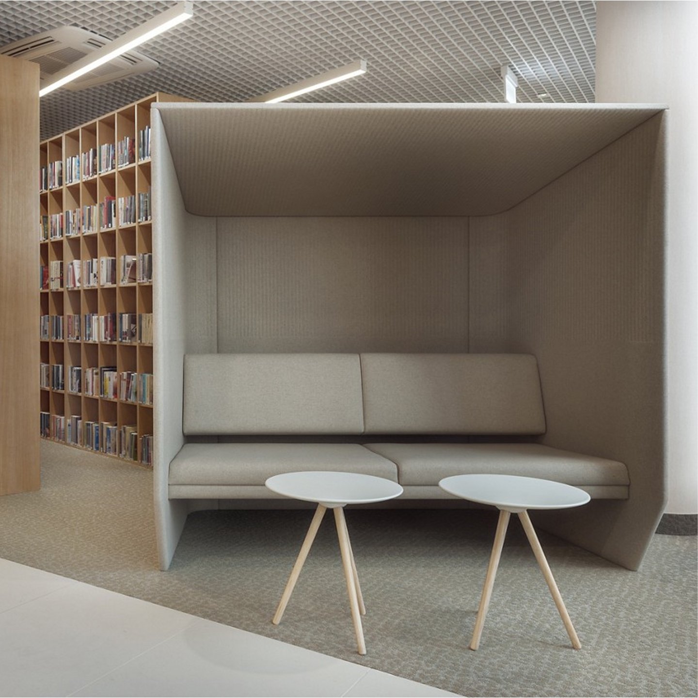 Haworth BuzziHub Booth in grey color with white tables at it in a office library 