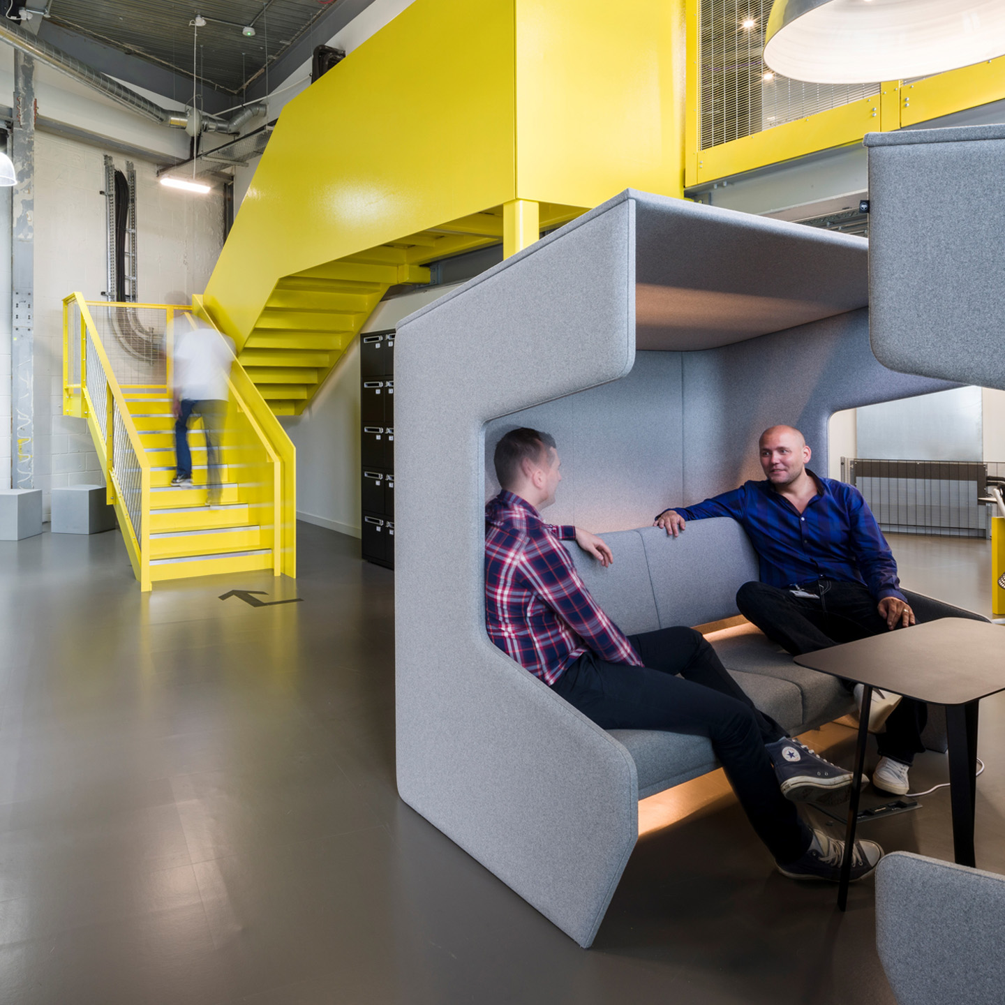 Haworth BuzziVille Hub Booth in grey color in open office space with employees talking at them