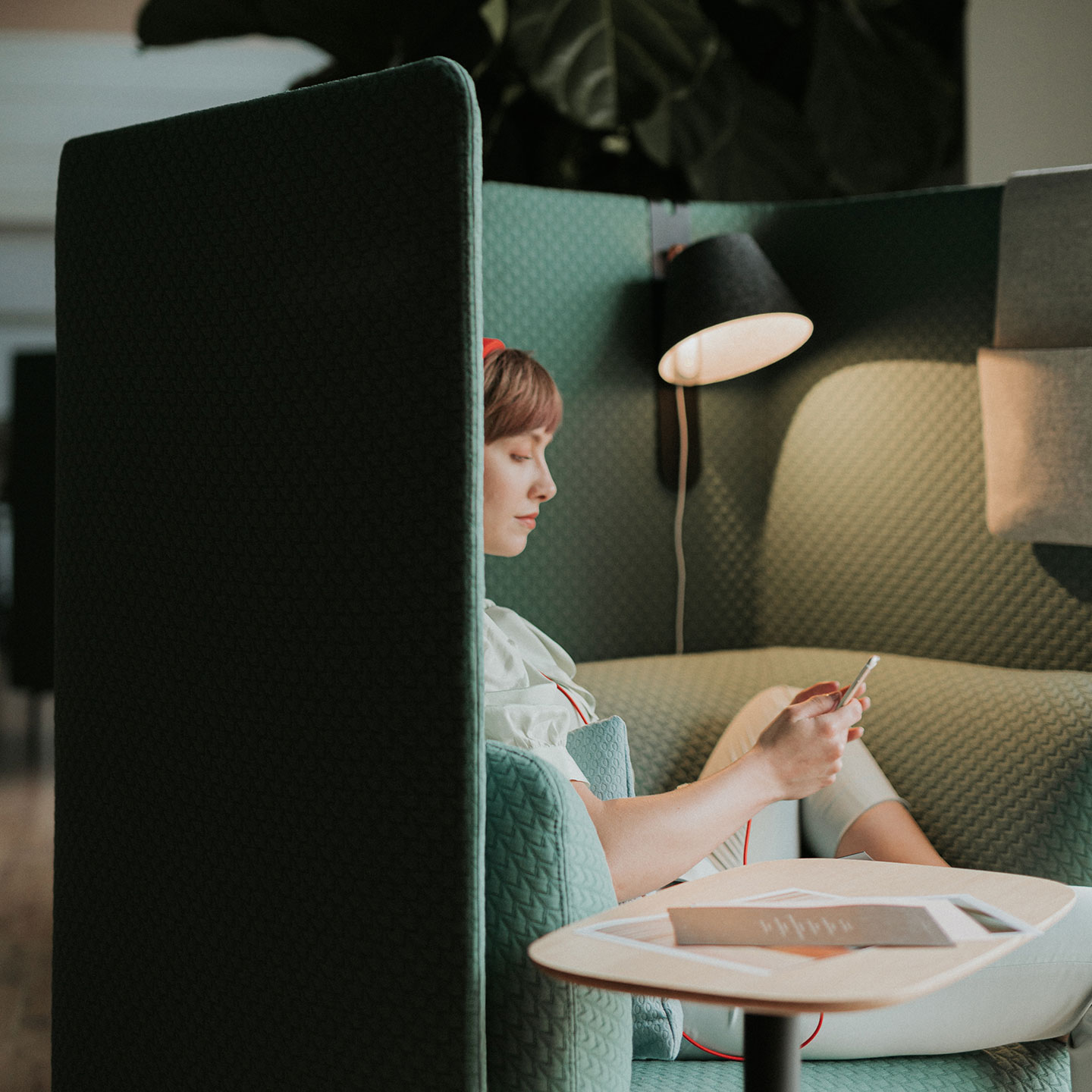 Haworth Cabana Lounge in green color with employee working at it with white table next to lounge