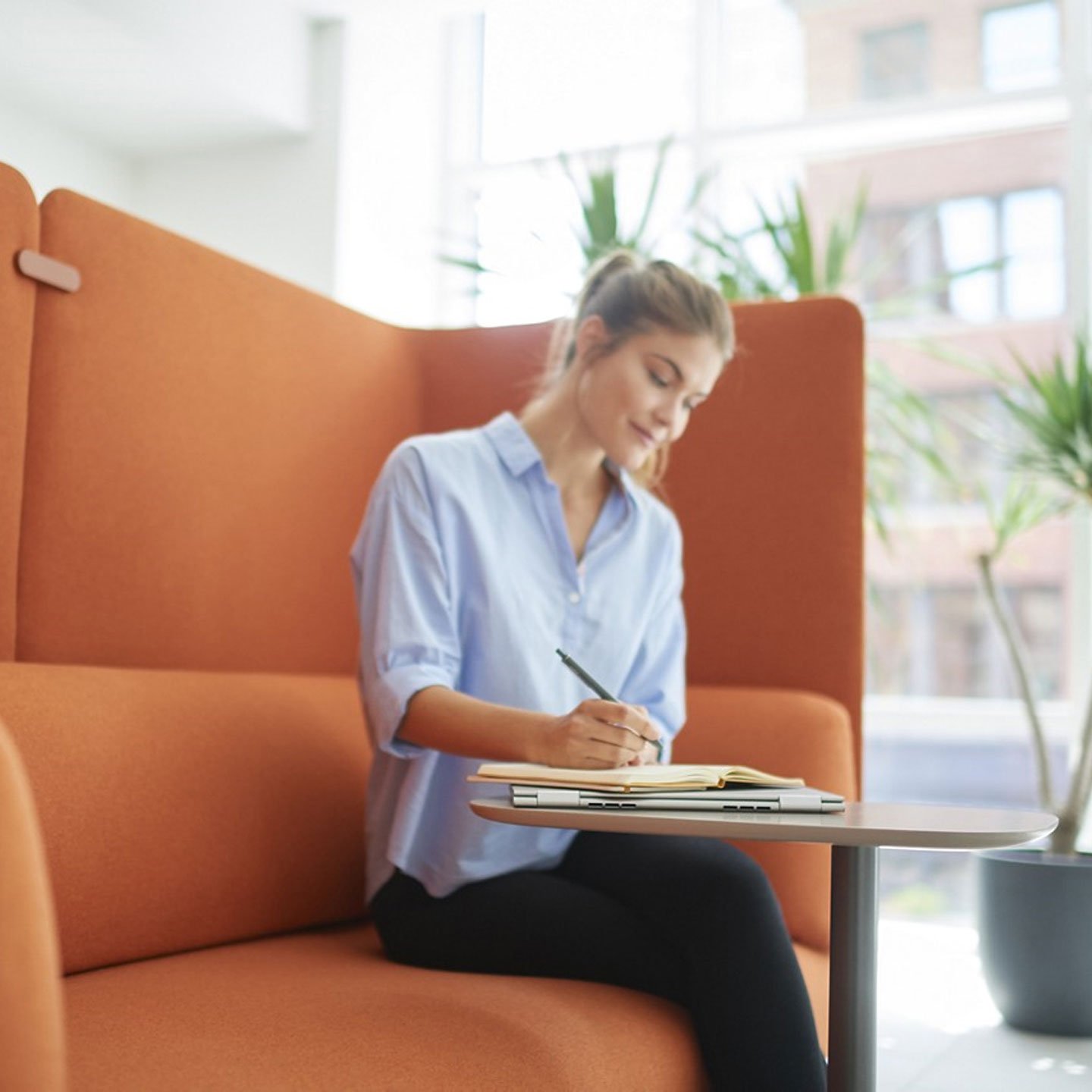 Haworth Cabana Lounge in orange color with employee working at small table in open office space