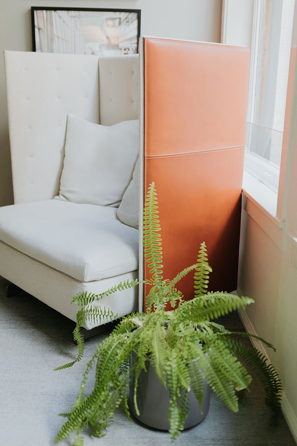 Haworth GranTorino HB Booth in white color and orange back in room corner with fern next to it