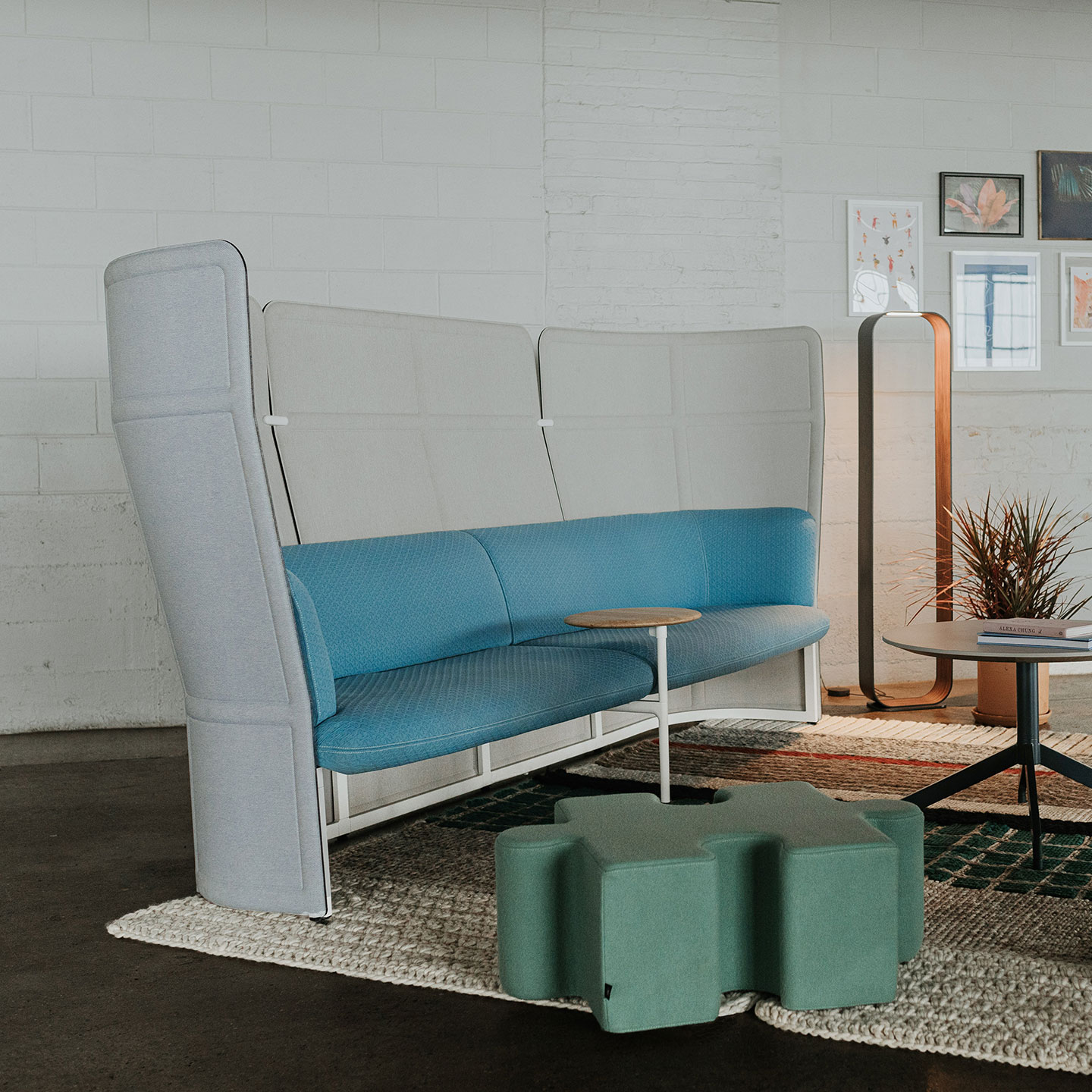 Haworth Openest Double Booth in grey color with blue seating and small wood table in open office space next to lighting space and puzzle ottoman