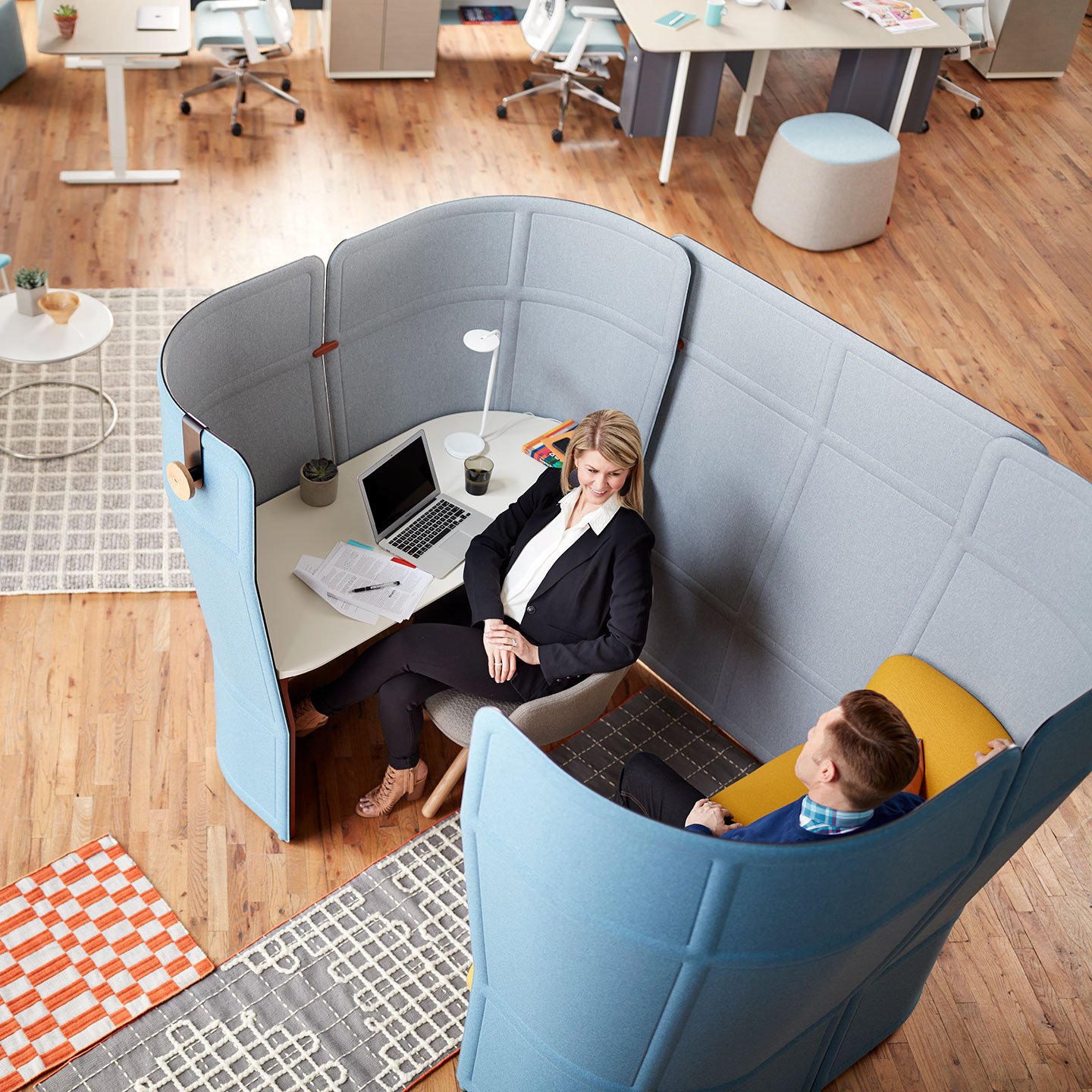 Haworth Openest Privacy Booth in blue color and grey inside with white desk and yellow seating with employees working inside the booth in open office space