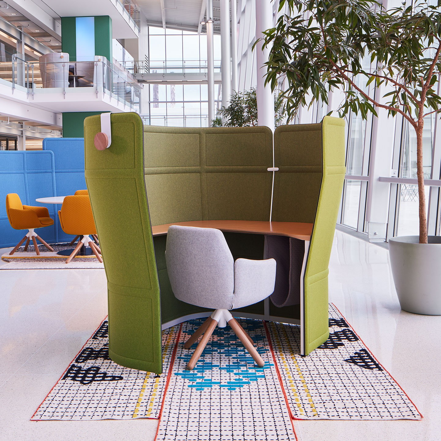 Haworth Openest Privacy Desk Booth in green color with wood table and grey chair at the booth in open office space