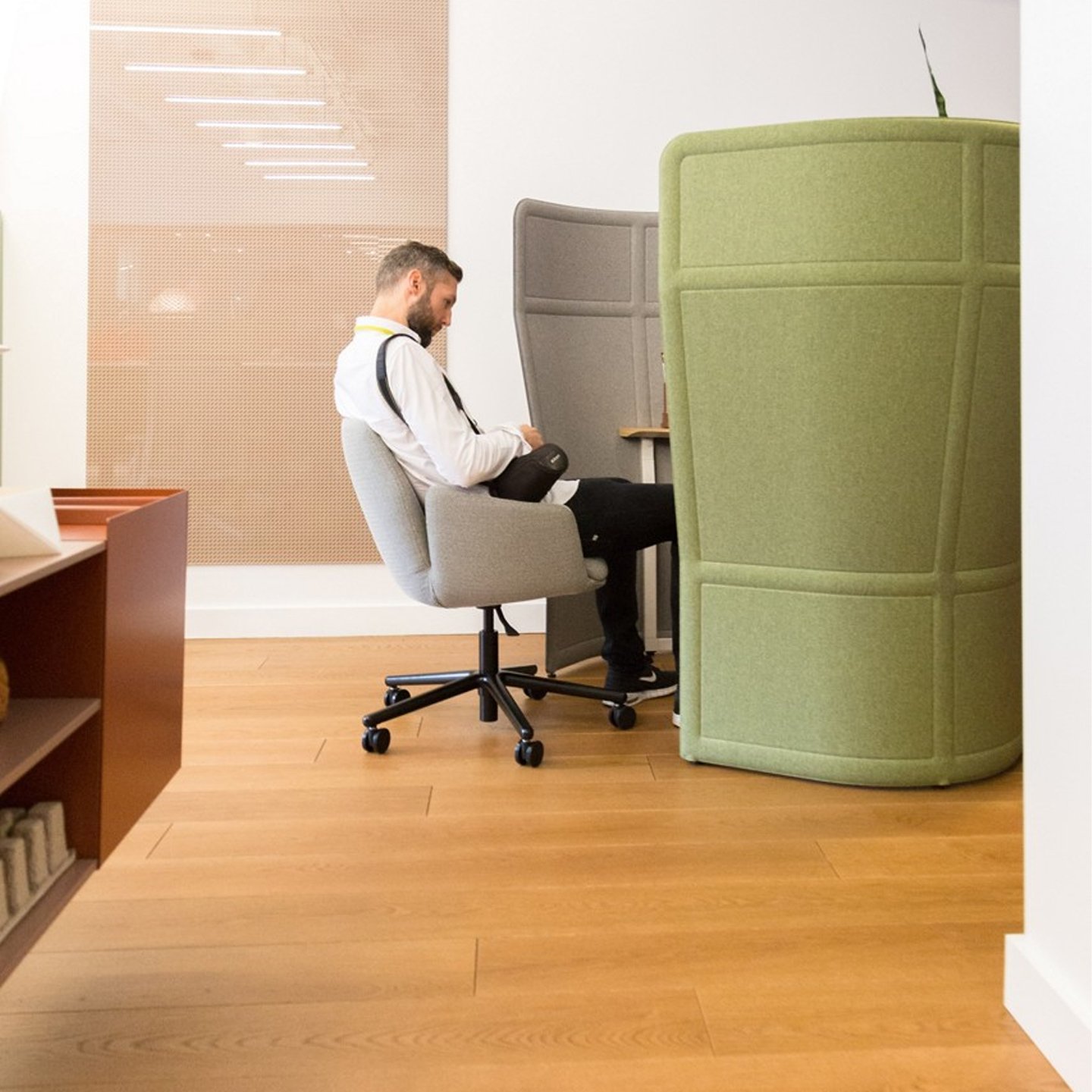 Haworth Openest Privacy Desk Booth in grey and green color with employee in grey chair at the desk in open office space