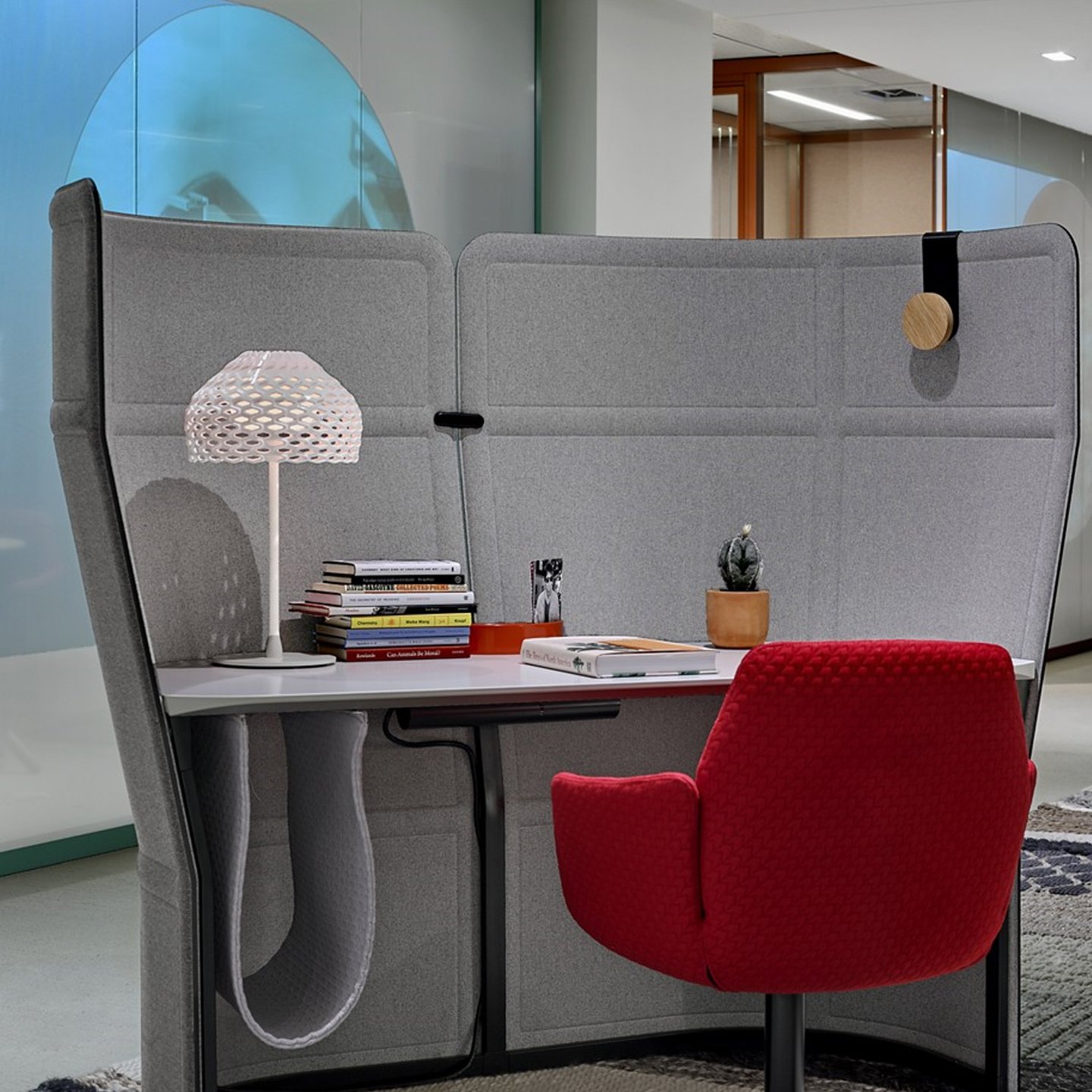 Haworth Openest Single Desk Booth in grey color with red chair at white desk and books on desk in open office lounge space