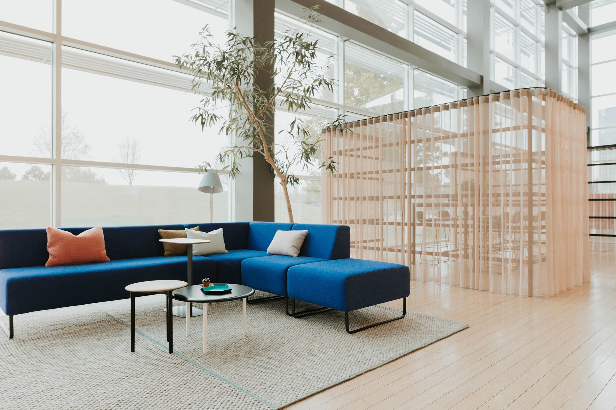 Haworth Riverbend and Pebble Booth in blue color with small center tables in open office area 