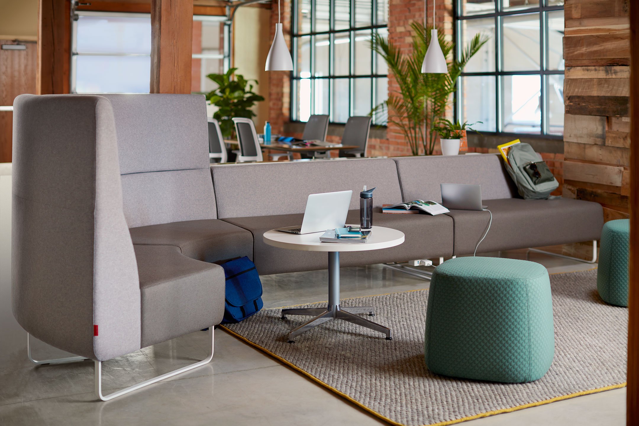 Haworth Riverbend and Pebble Booth in grey color with white table with laptop and water bottle on it in open office work area