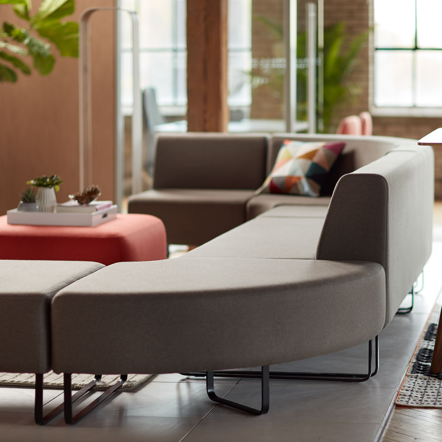 Haworth Riverbend and Pebble Booth in grey color with red ottoman as center piece in open office space