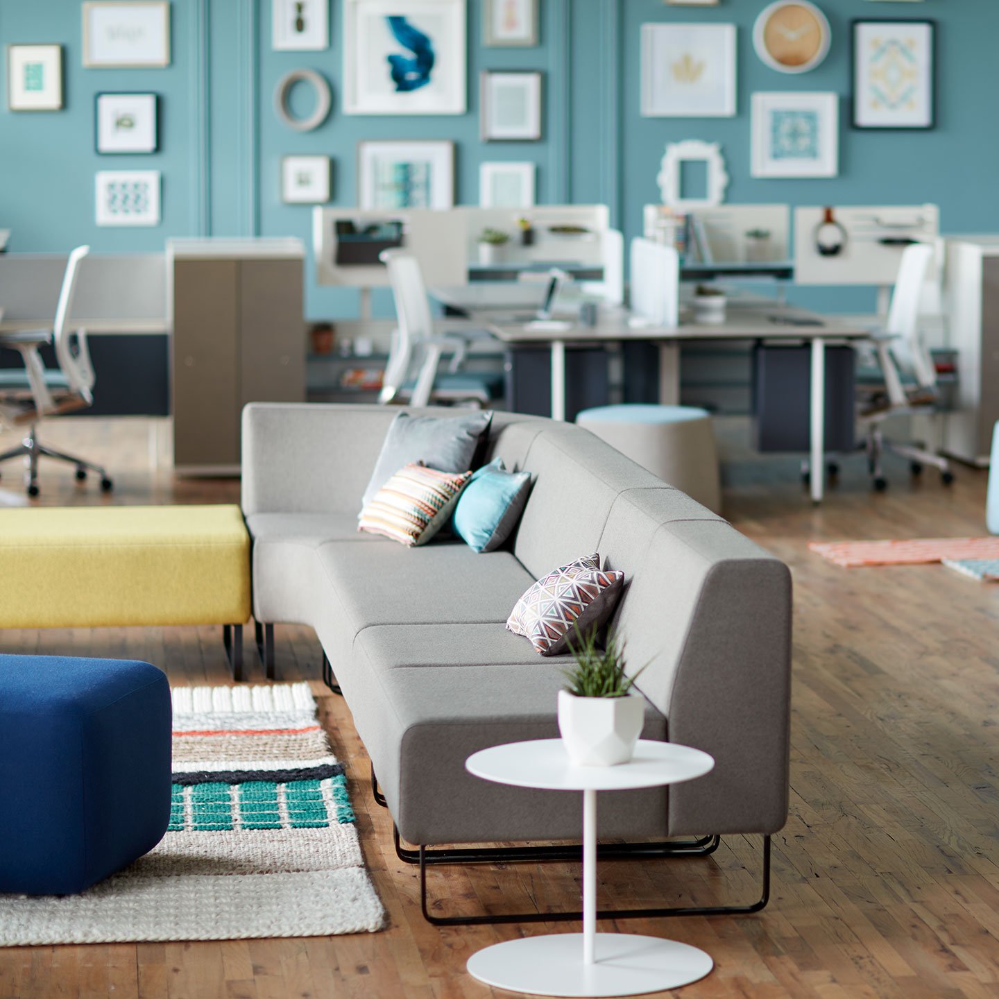 Haworth Riverbend and Pebble Booth in grey color with yellow and blue ottomans and white side table in open office space