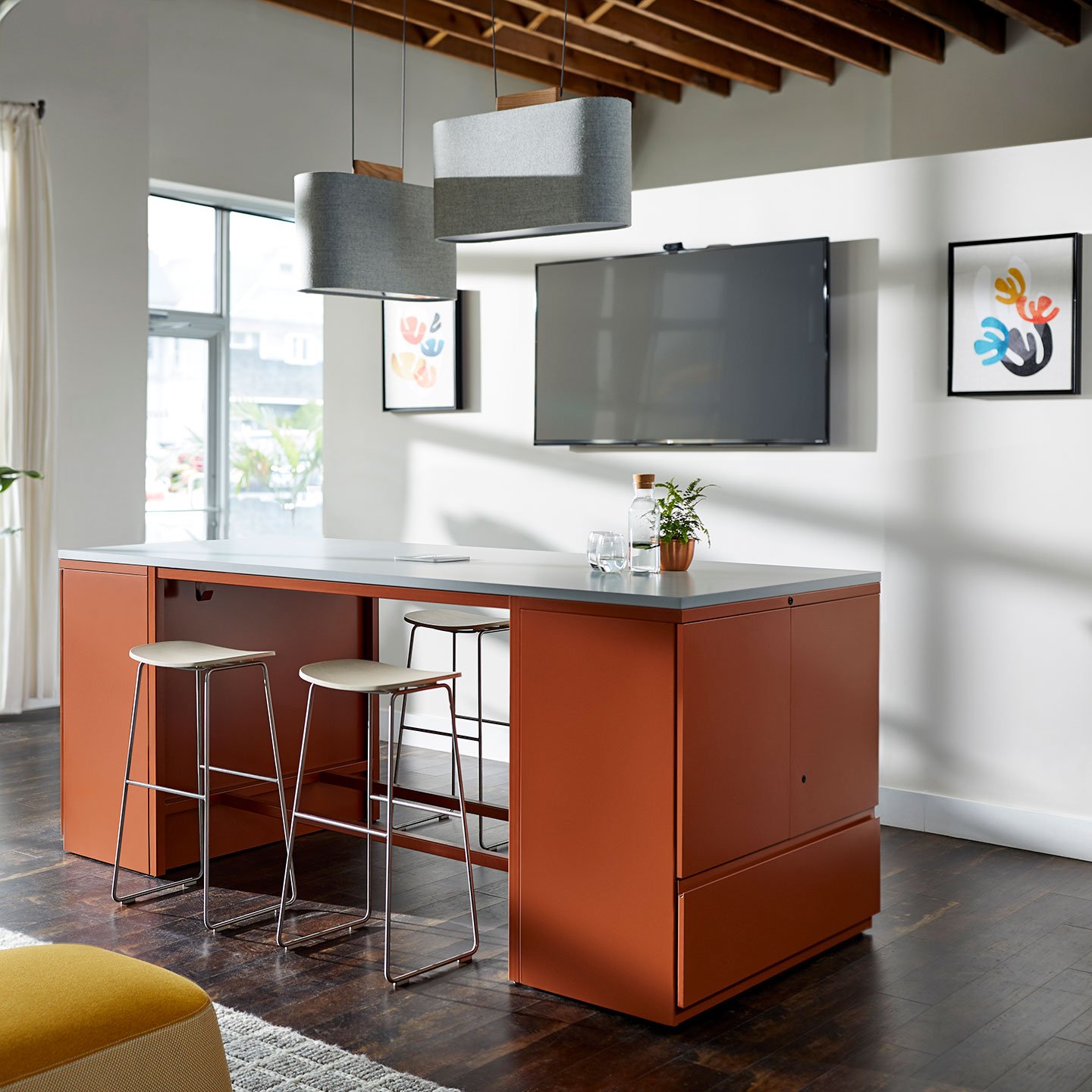 Haworth Belmont Lighting in grey color in office lounge space with orange desk and high chairs with tv on wall