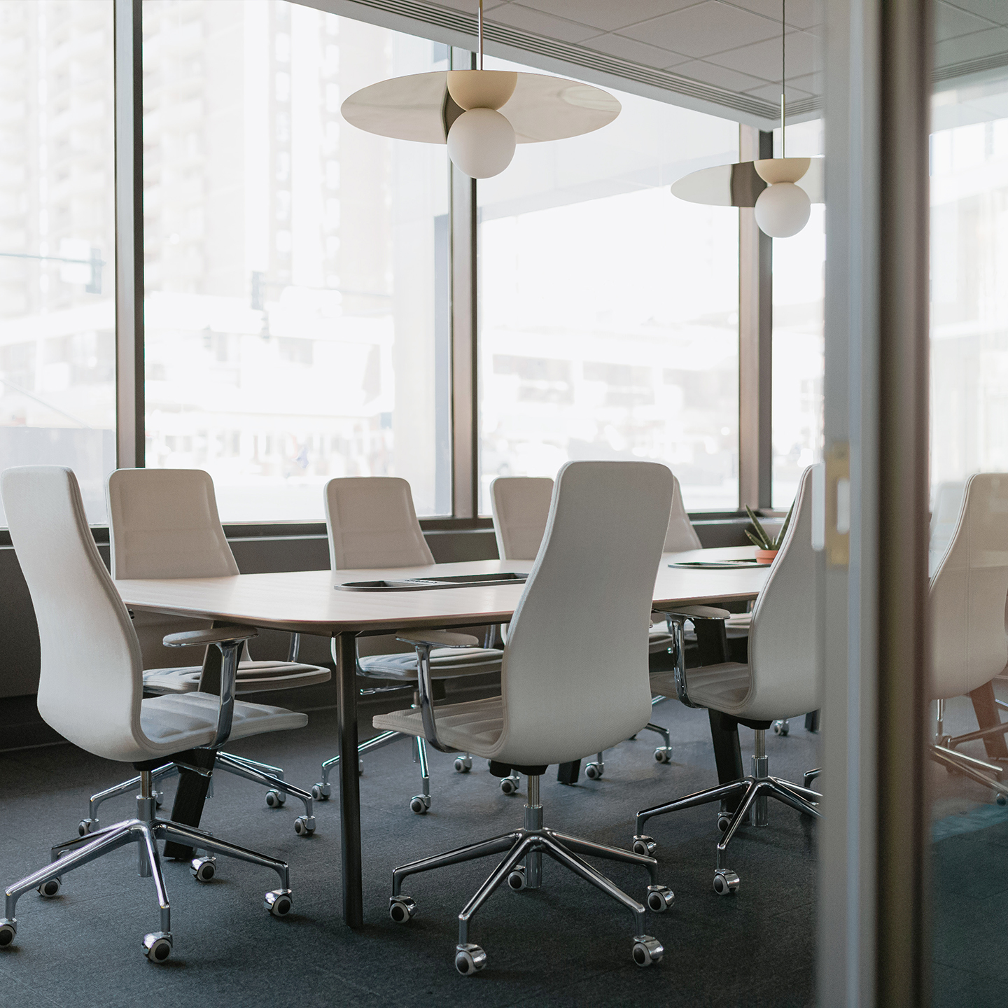 Haworth Bola Disc Lighting with metal disc over meeting table in private conference room with white chairs