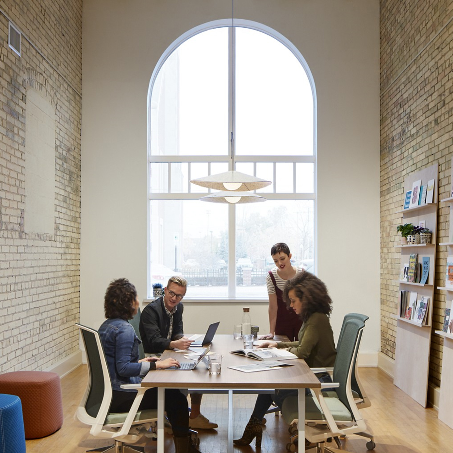 Haworth Bola Felt lighting above office meeting room where employees are working with brick walls and table and haworth chairs