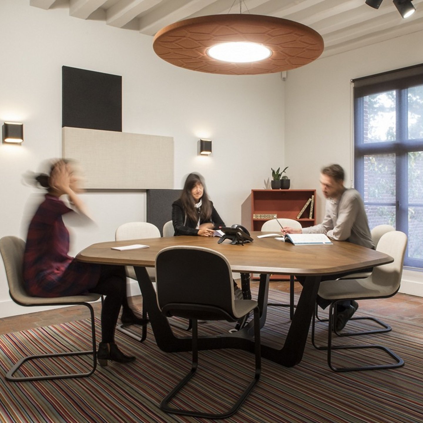 Haworth BuzziMoon Lighting in private collaboration room with employees working on oak desk and white chairs