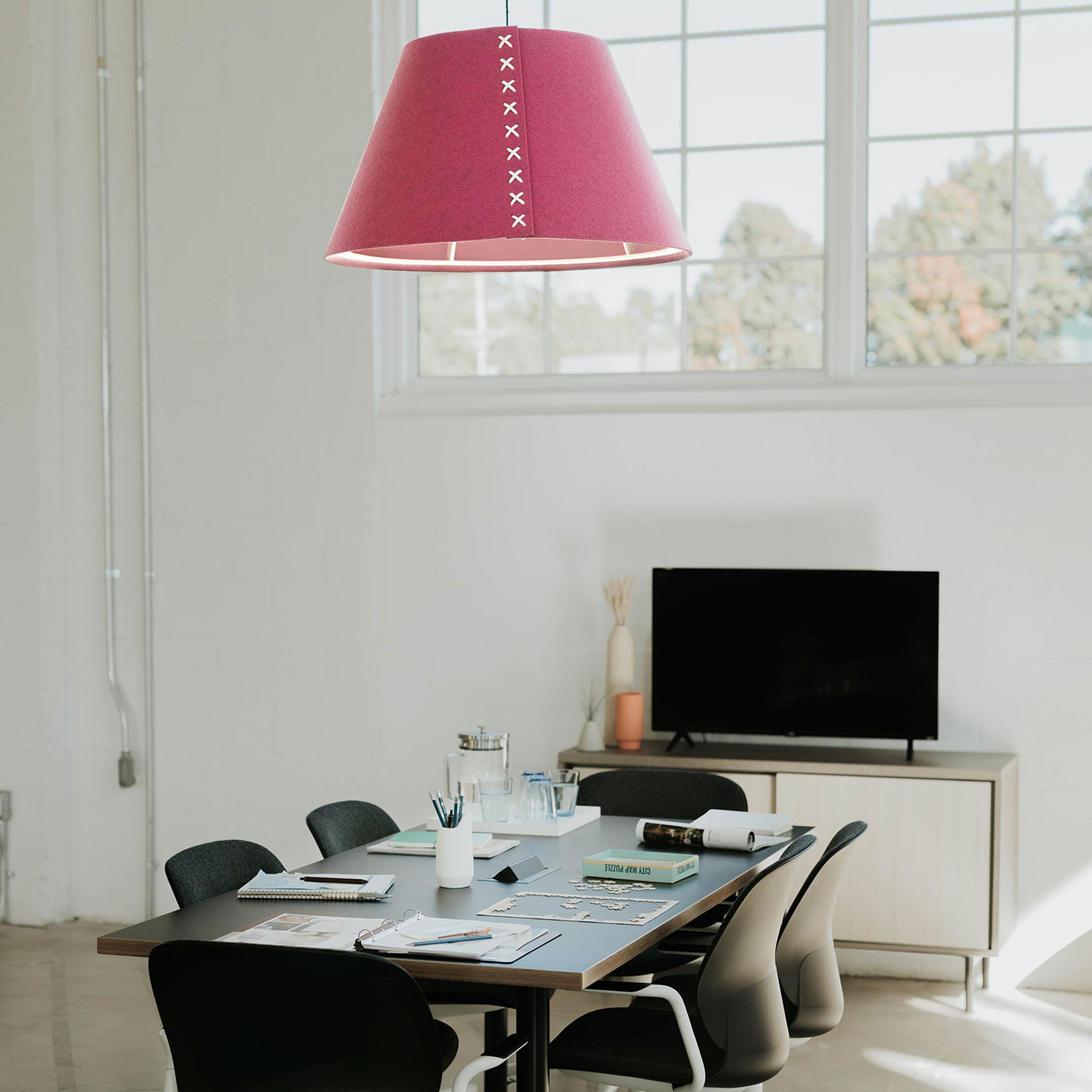 Haworth BuzziShade lighting in pink above small black table with black chairs in private meeting room