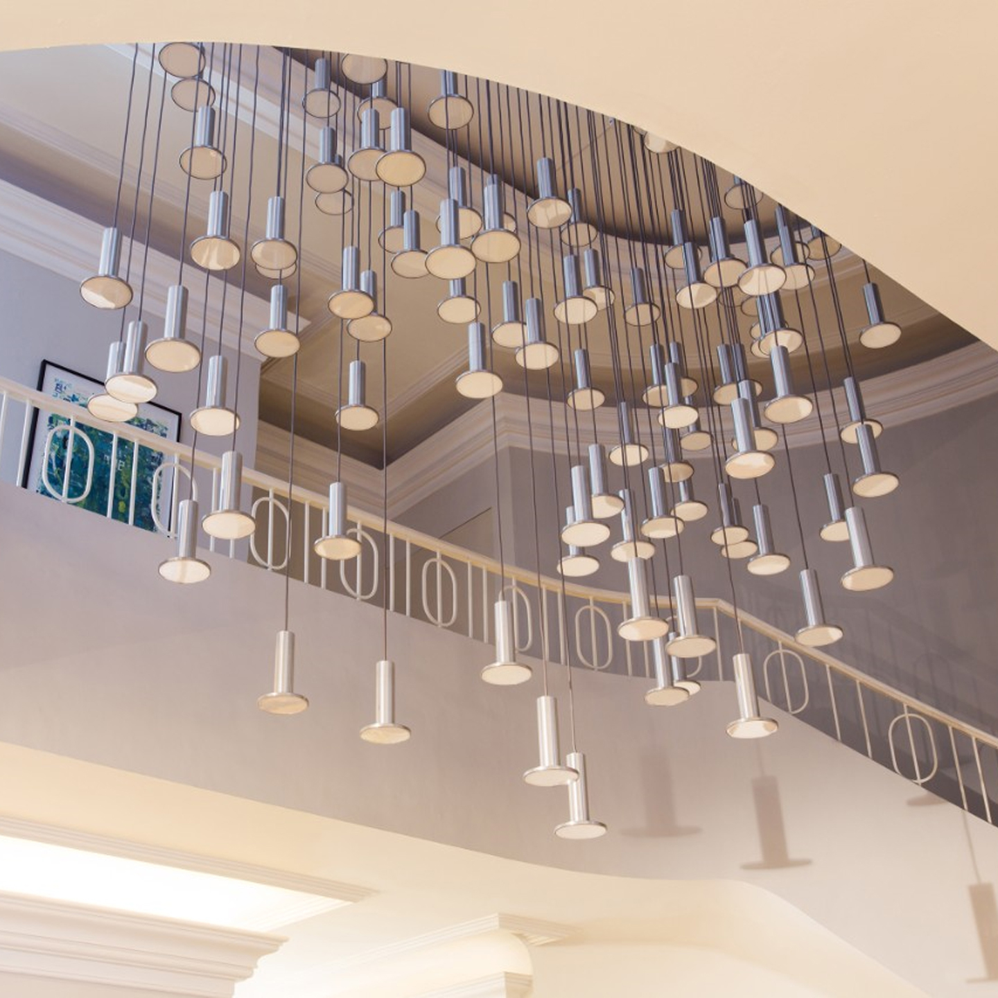 Haworth Cielo Lighting hanging down from ceiling in grand stair case with white walls and railing