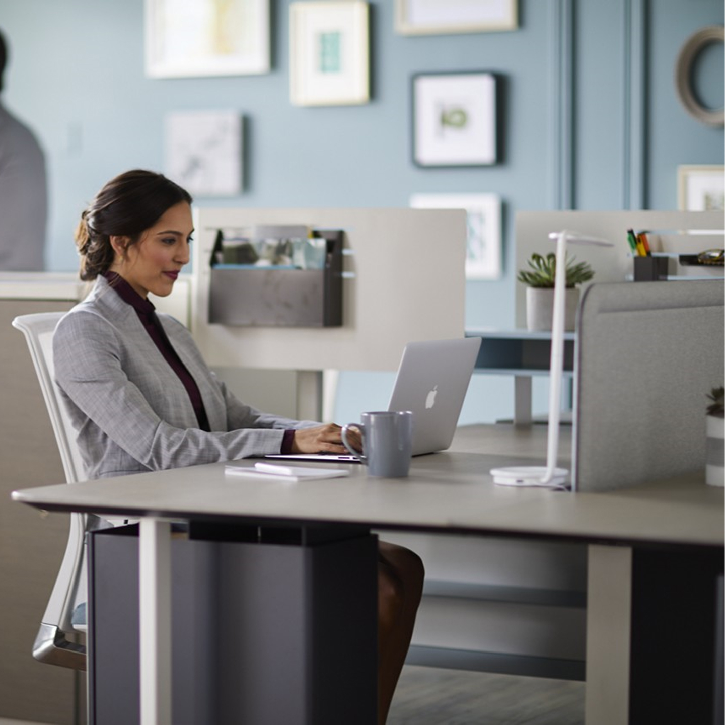 Haworth Pixo Lighting in white color on office desk with employee working on laptop in open office space