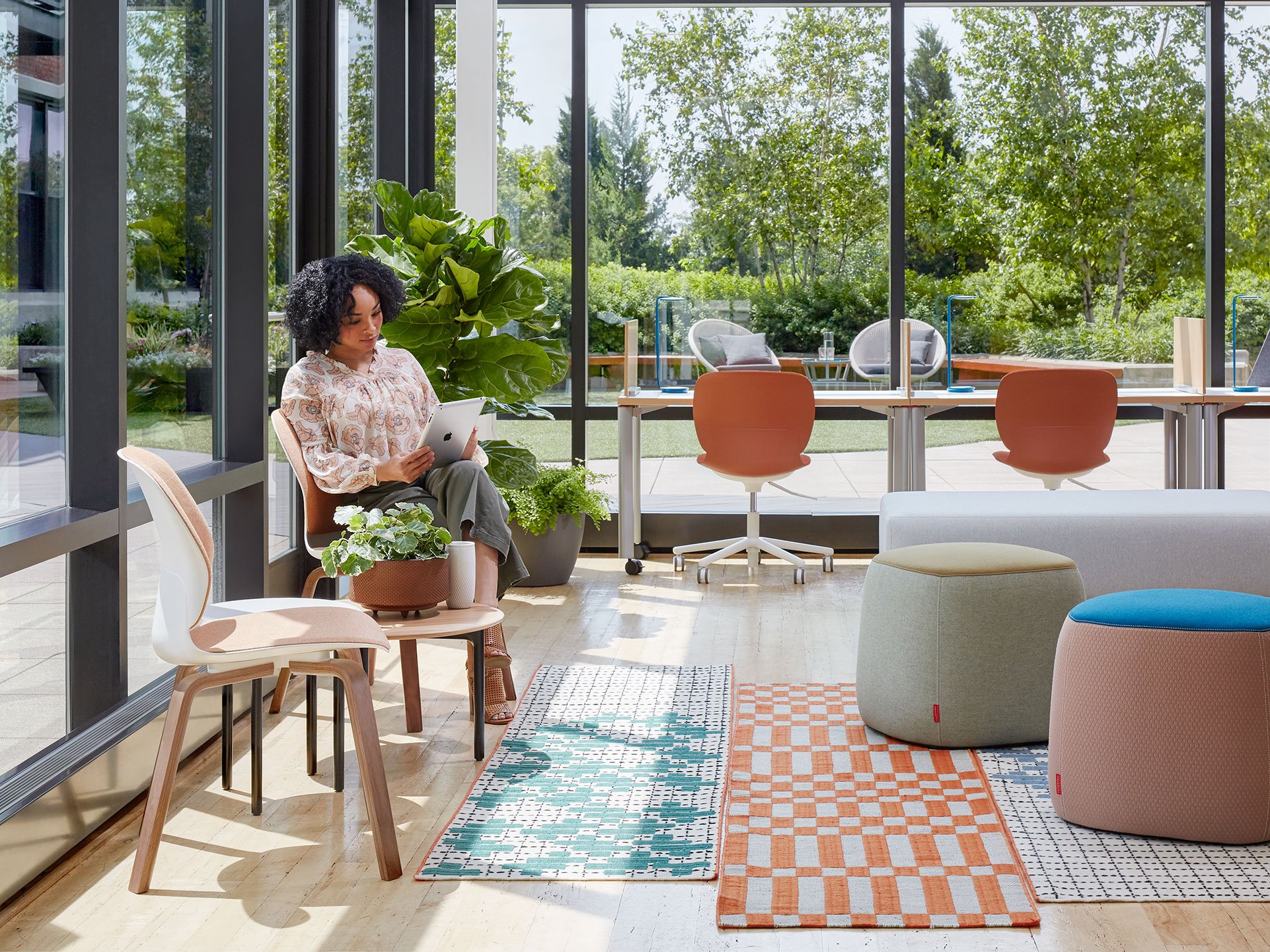 Haworth Bandas Space Rug in white and orange in open office lounge area with employee sitting in chair working on tablet