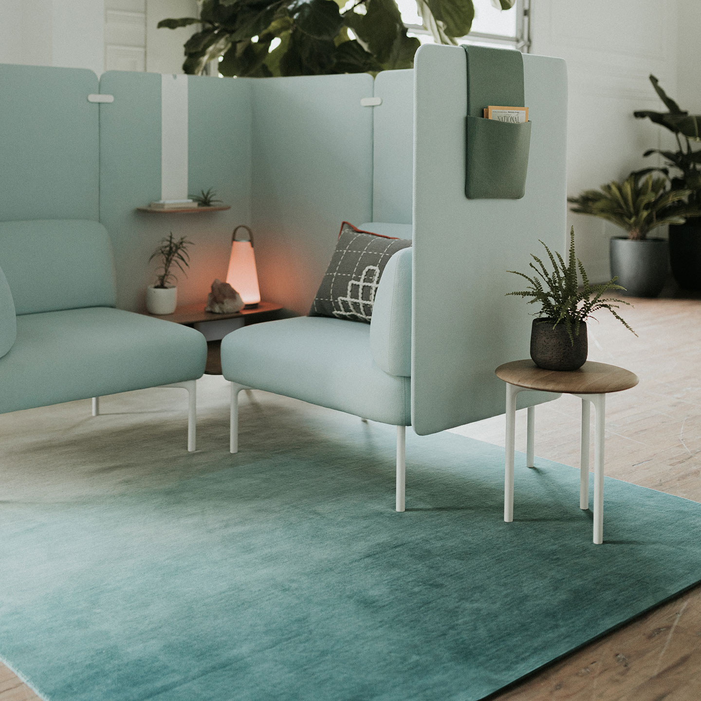 Haworth Hand Knotted Degrade Rug in blue and white color under private couch with booth in blue color with small table next to it in open office space