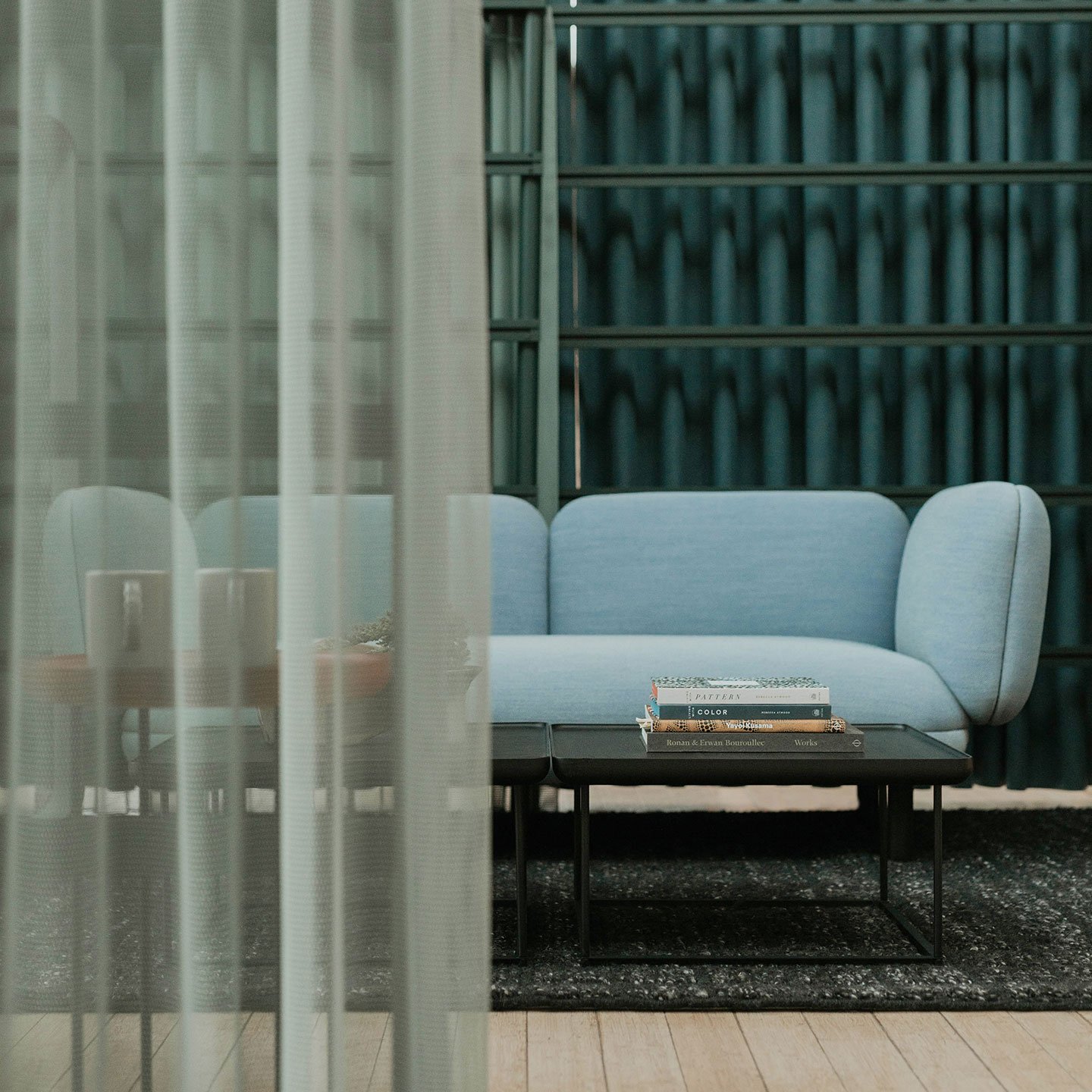 Haworth Mangas Natural Rug in black color and sqaure pattern in blue couch and black table covered by green privacy booth