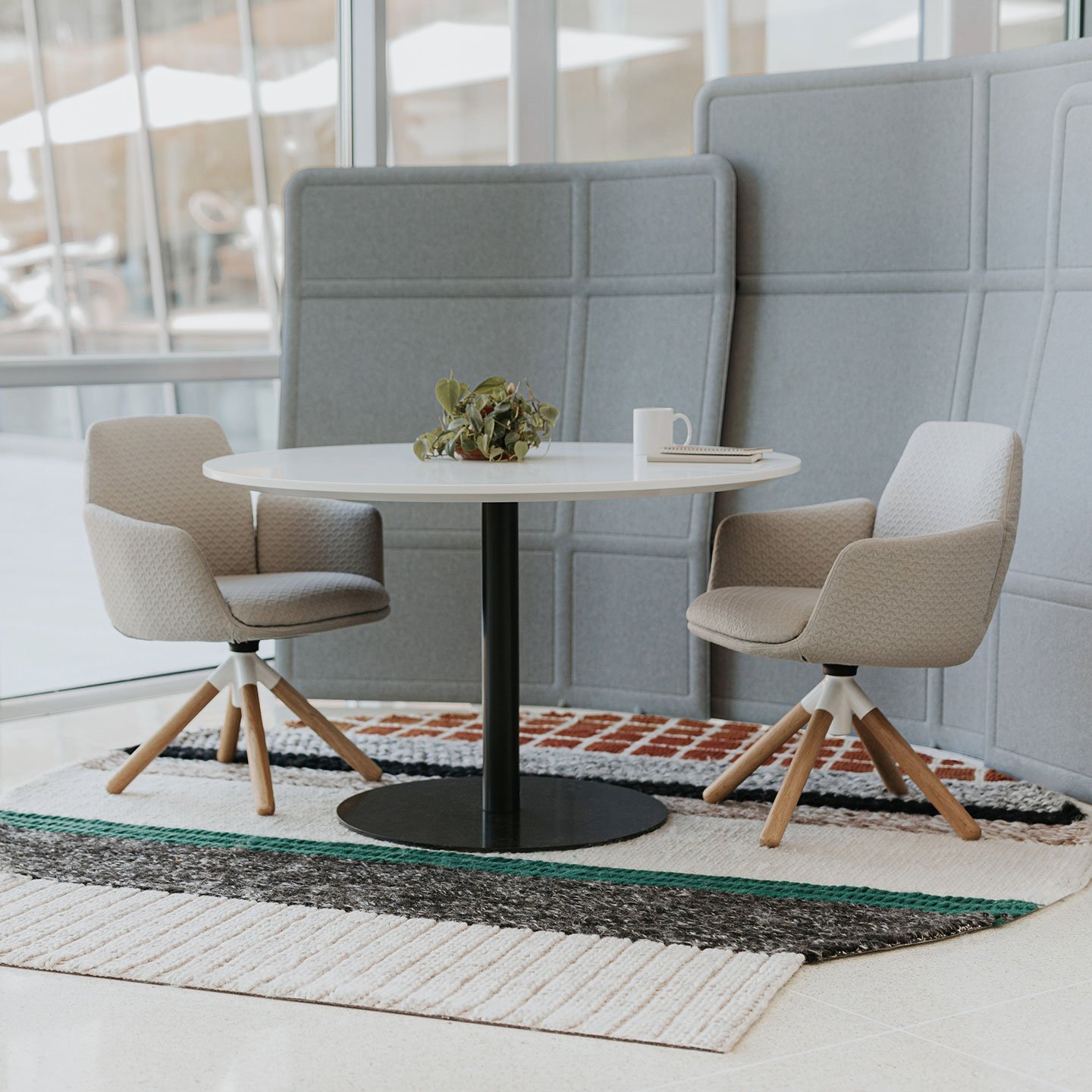 Haworth Mangas Original Rug in multiple colors and circular shape under white table and grey chairs with haworth privacy booth in grey in open office space
