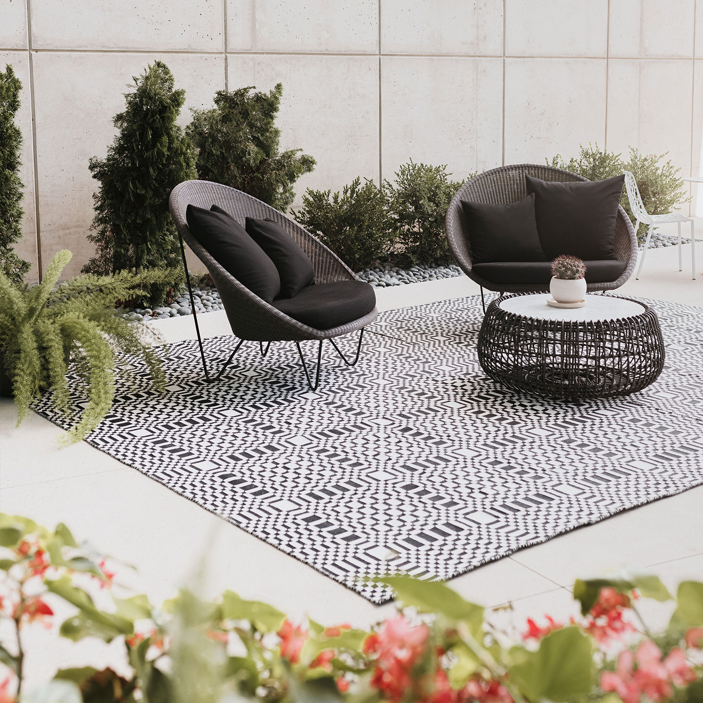 Haworth Patch Rug in black and white with square pattern under black patio chairs and table in an outdoor patio