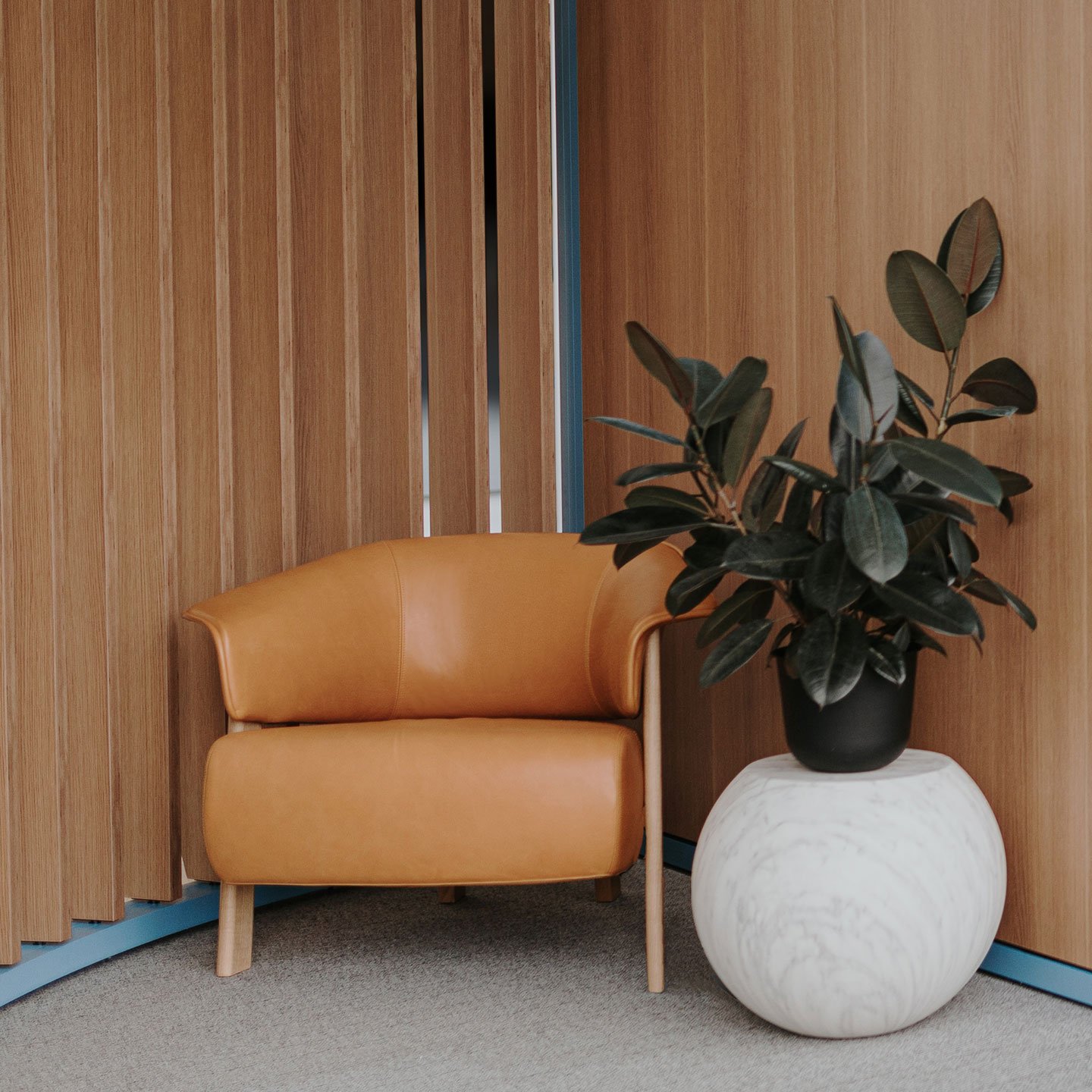 Haworth Back Wing chair in tan leather next to a potted plant