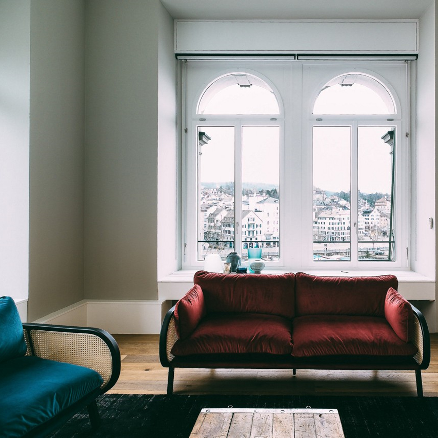 Haworth Buzzicane lounge chairs in red and teal velvet fabrics overseeing buildings through a window