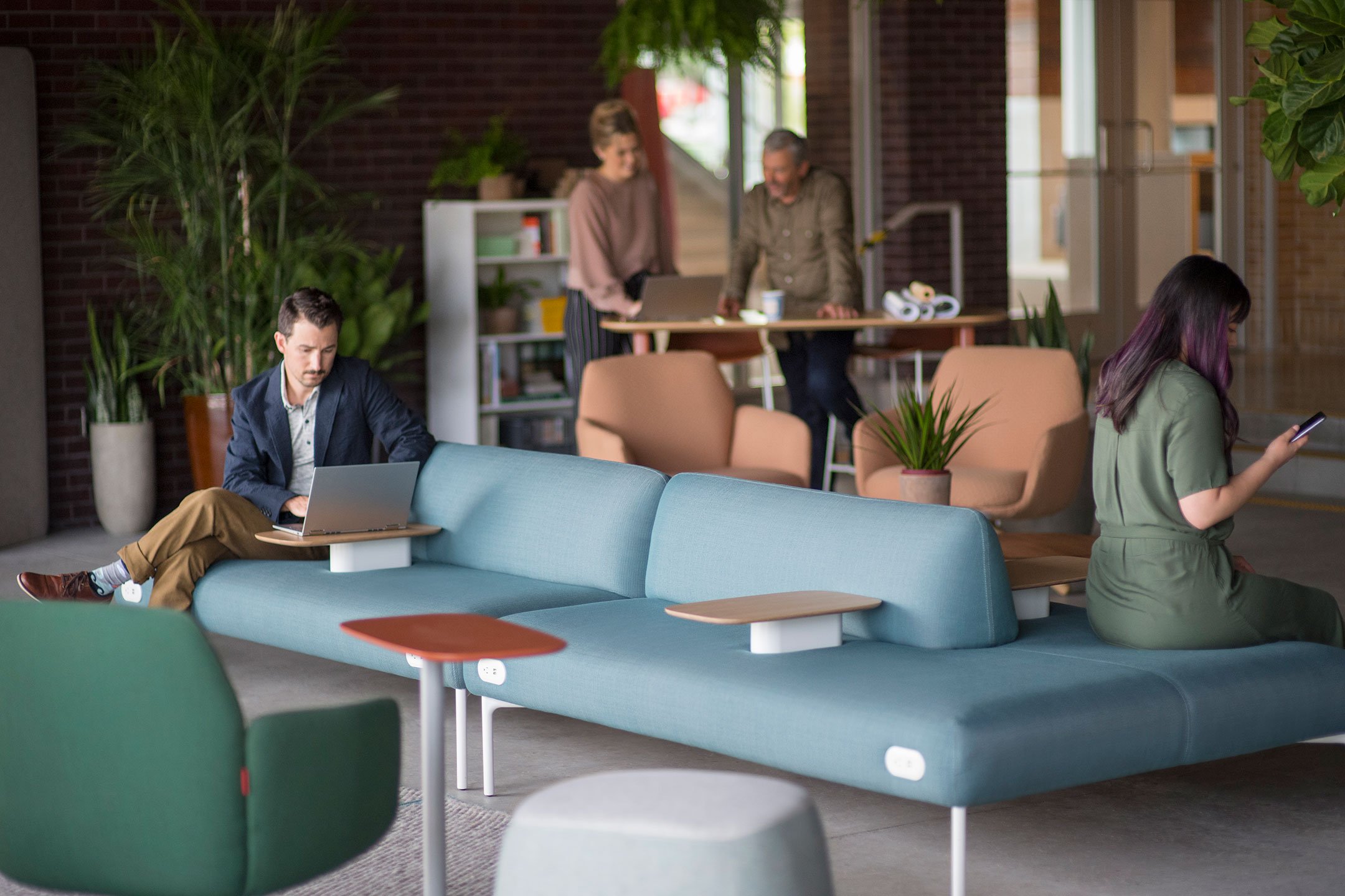 A bunch of coworkers using Haworth Cabana island lounge for a informal work discussion in a office common area