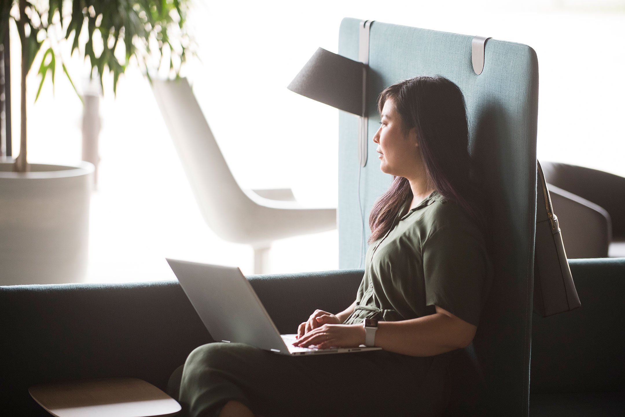 A coworker using Haworth Cabana island lounge in green color for a casual workspace