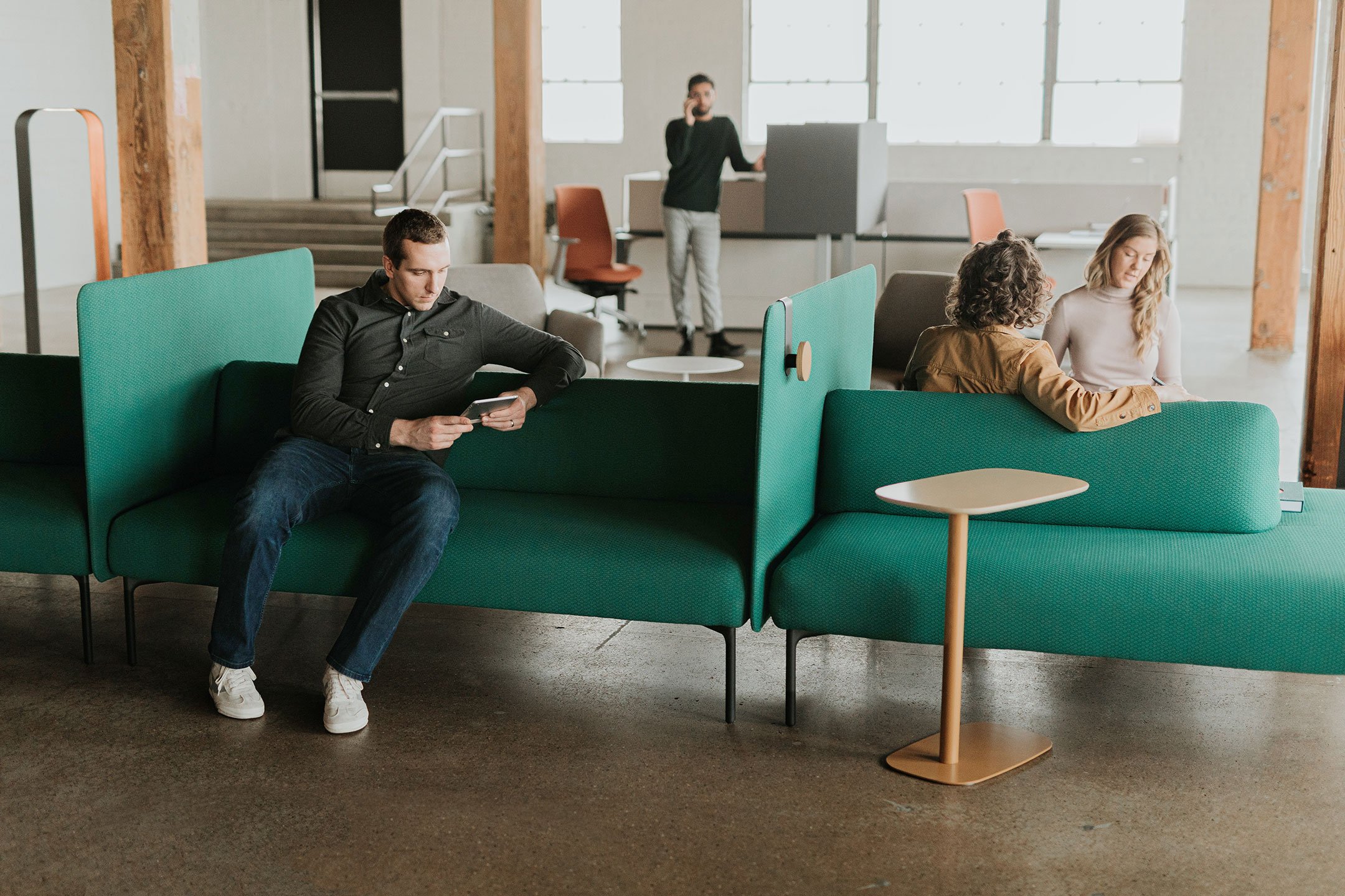 A group of coworkers using the Haworth Cabana island lounge in green color for casual discussions and meetings in a office open space