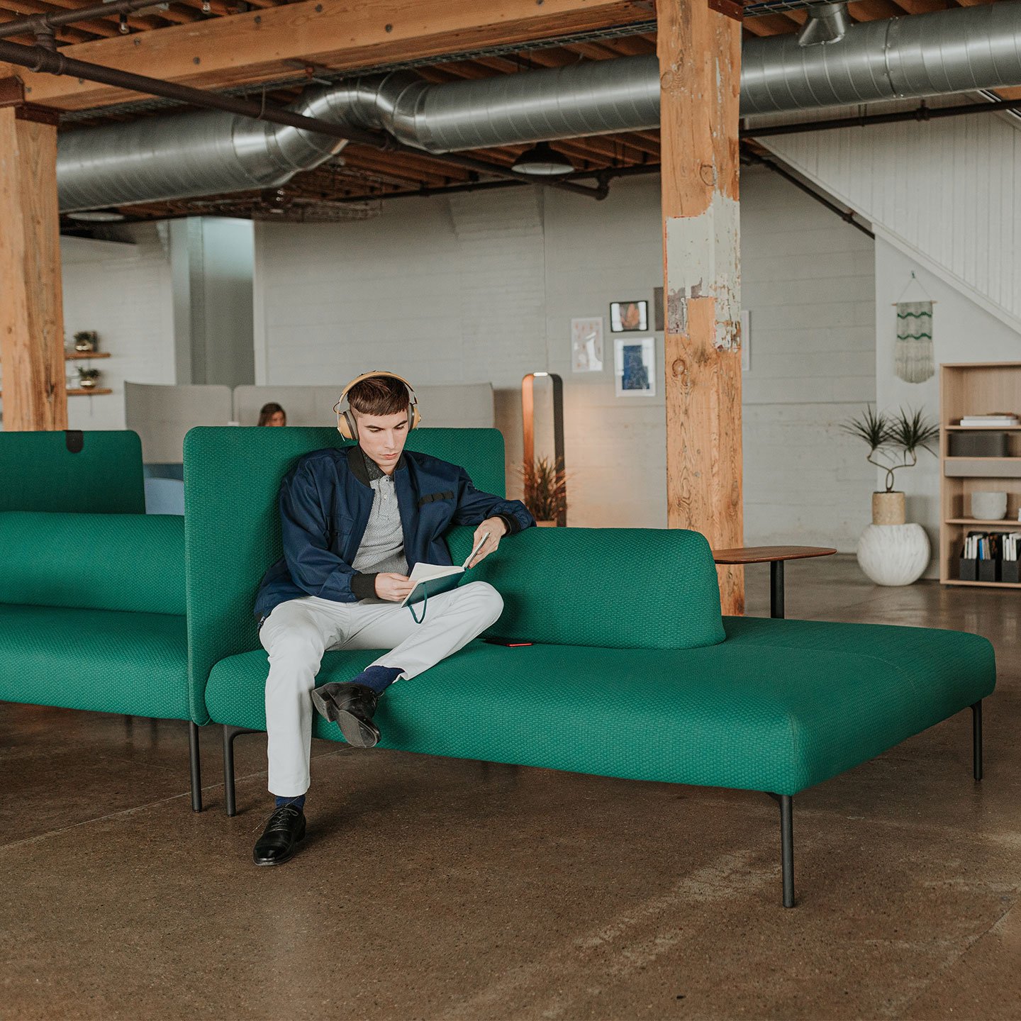 Haworth Cabana lounge island in green color being used by a coworker as a casual seating in the office space