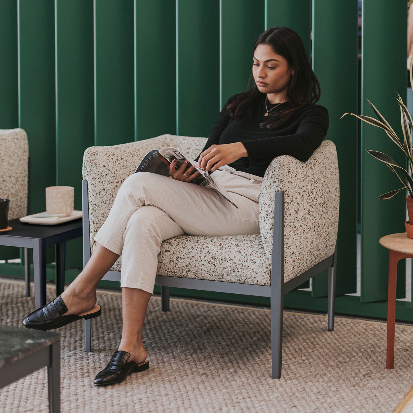 A lady seated comfortably on a Haworth Cotone chair with printed off white upholstery in a casual setup